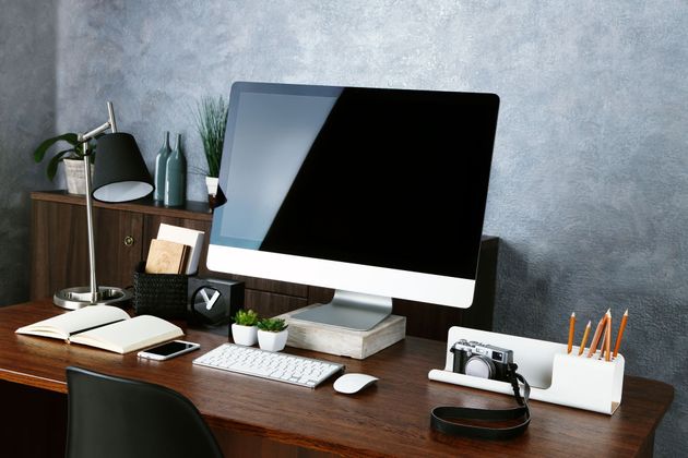 Modern desk setup with desktop computer, keyboard, books, plant, and stationery in a home office