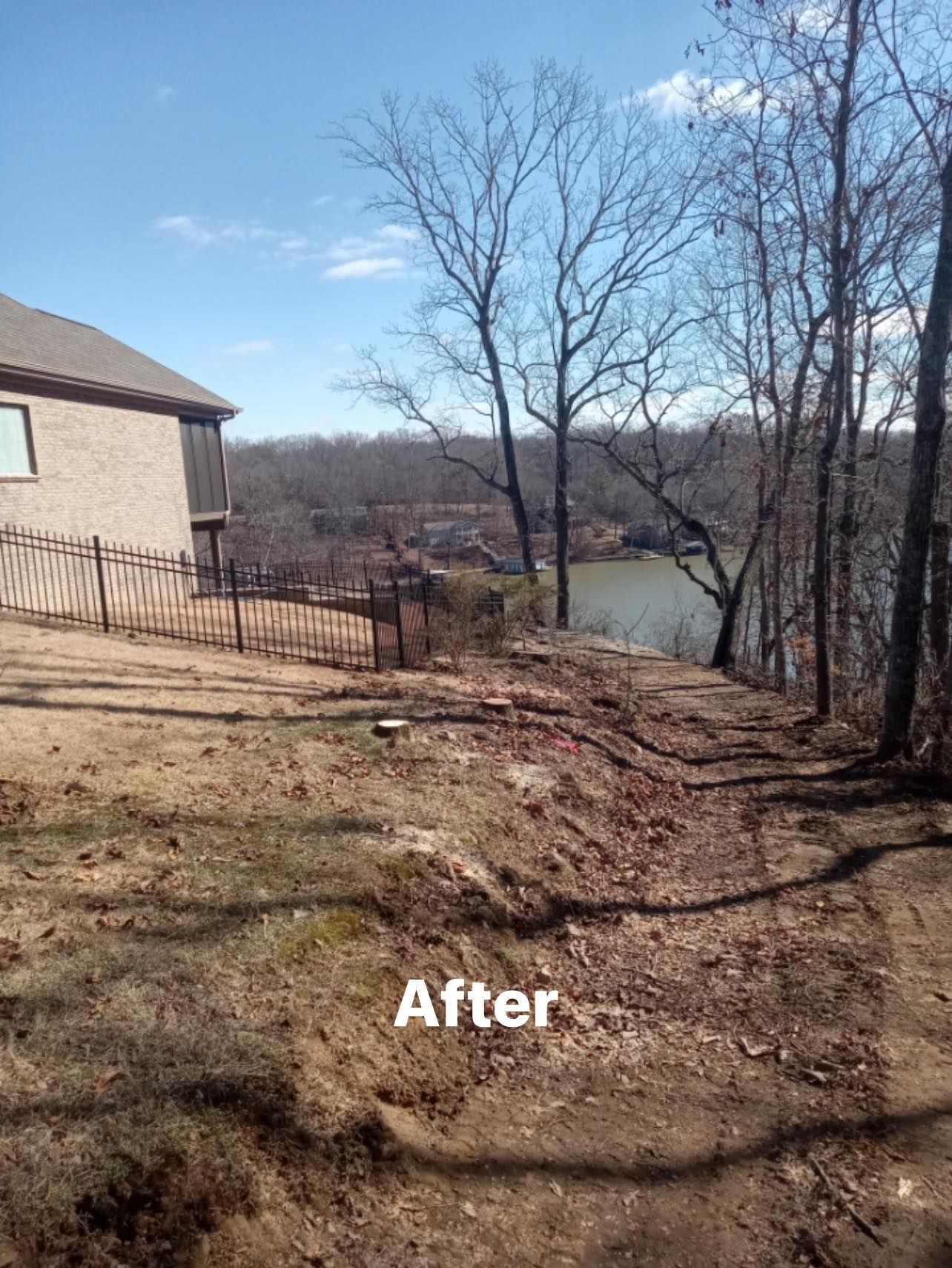 a house is sitting on top of a hill next to a body of water