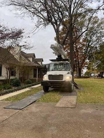 a white truck with a crane on top of it is parked in front of a house