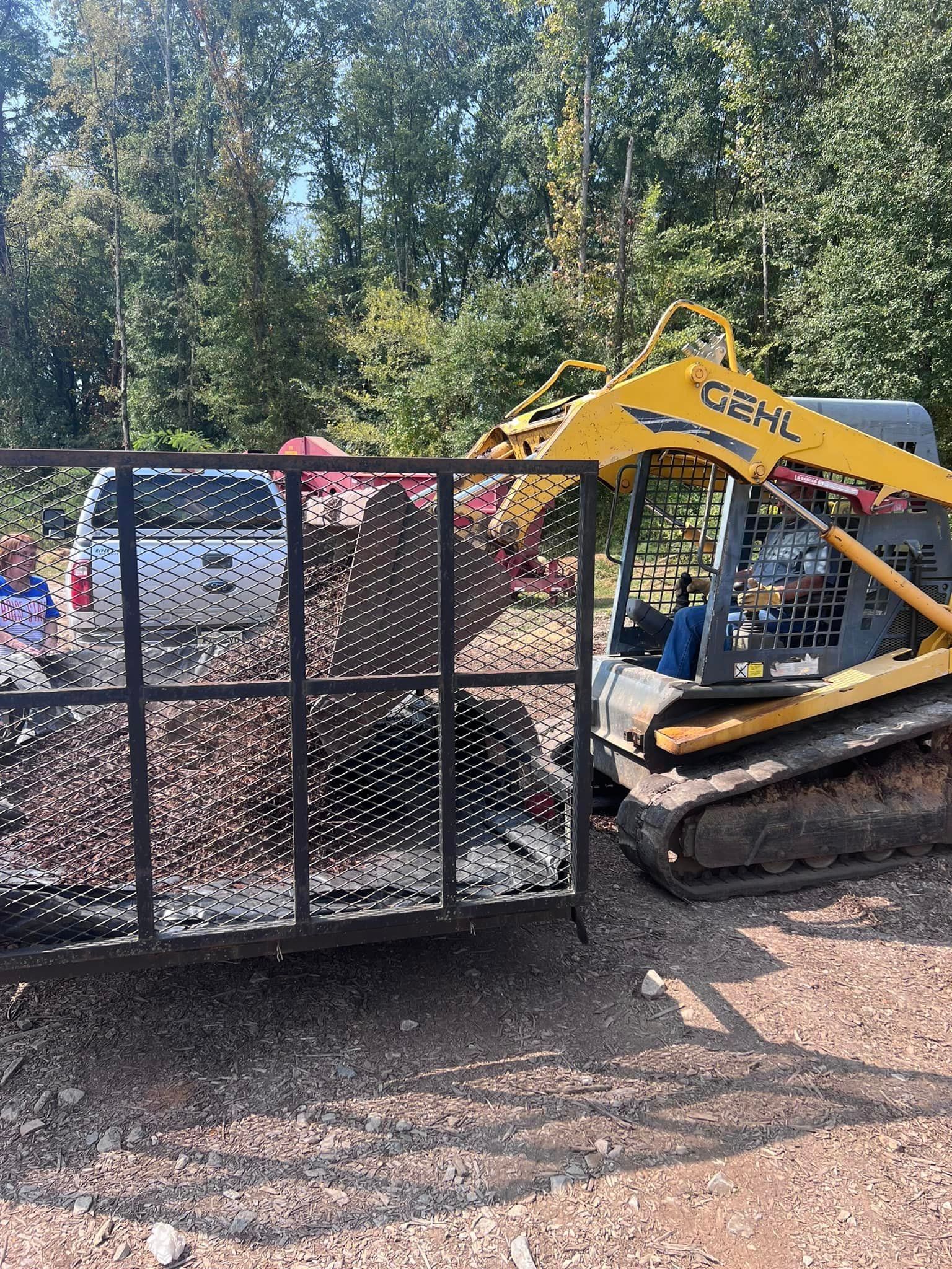 a yellow bulldozer is parked next to a fence in a gravel lot