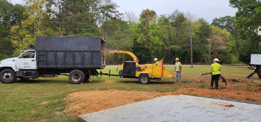 a dump truck is parked in a grassy field next to a tree chipper
