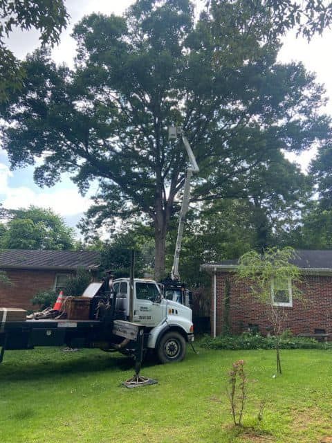 a white truck with a crane on the back is parked in front of a house .