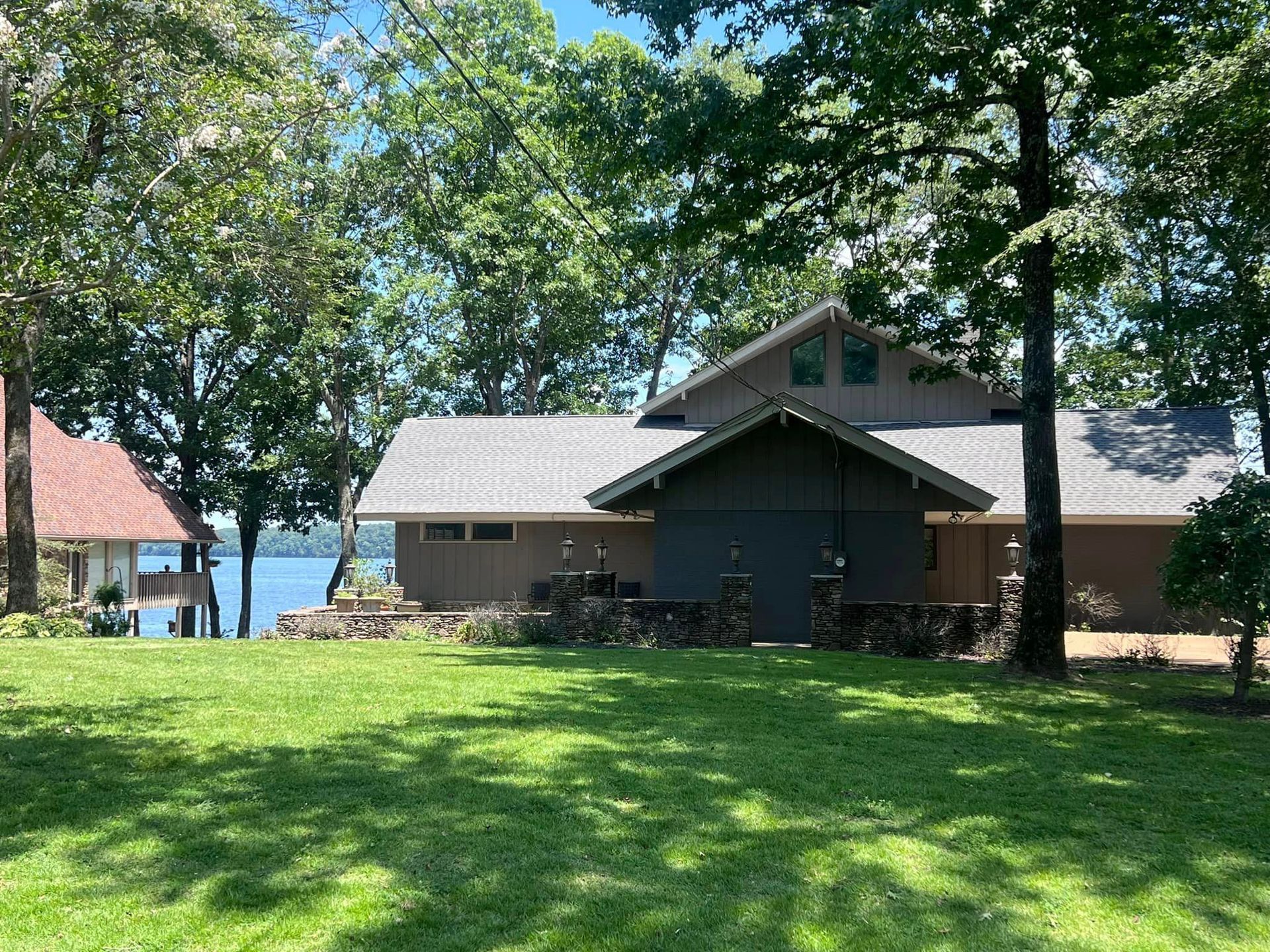a house with a large lawn in front of it and a lake in the background