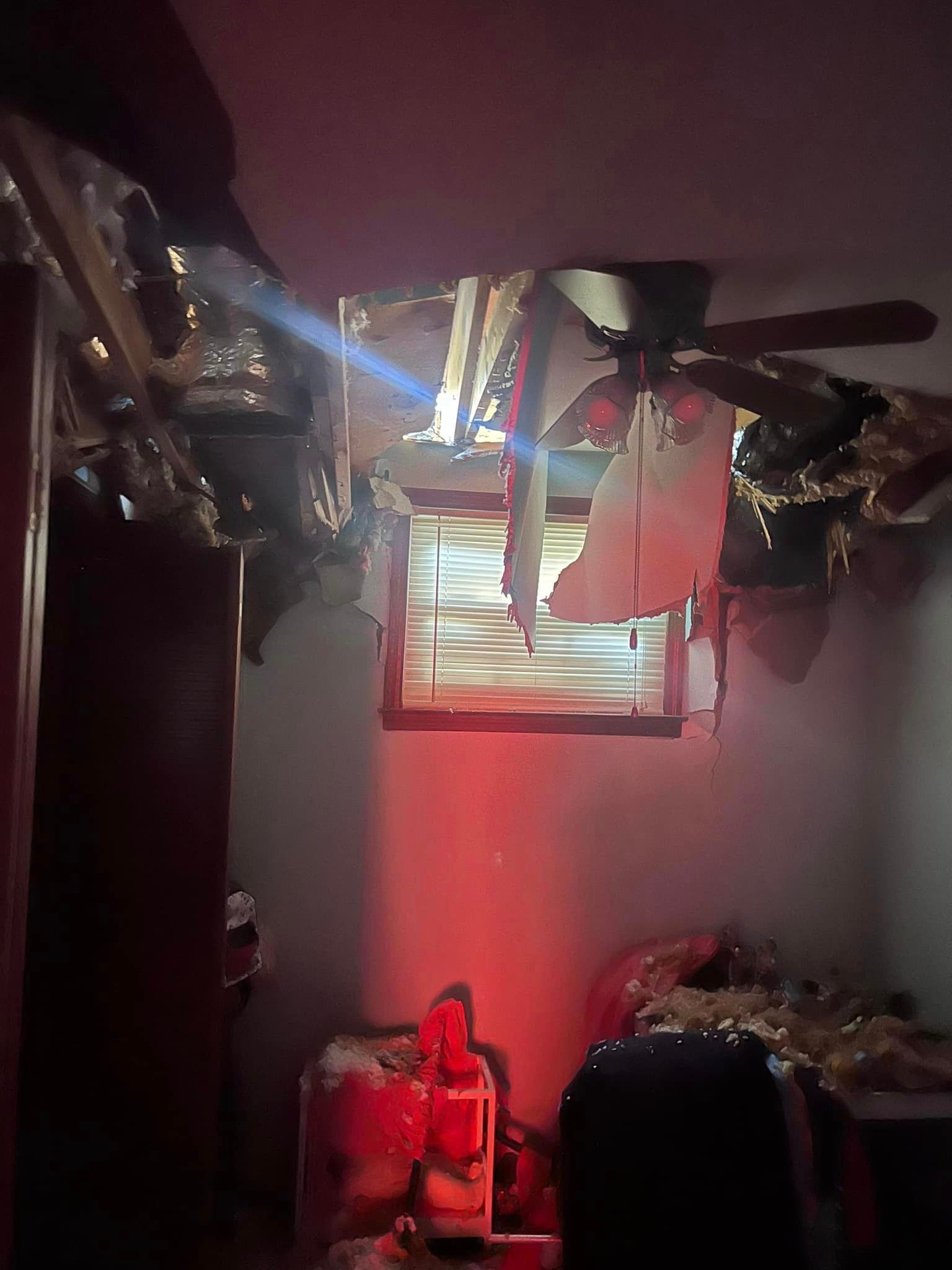 a dark room with a ceiling fan and a window