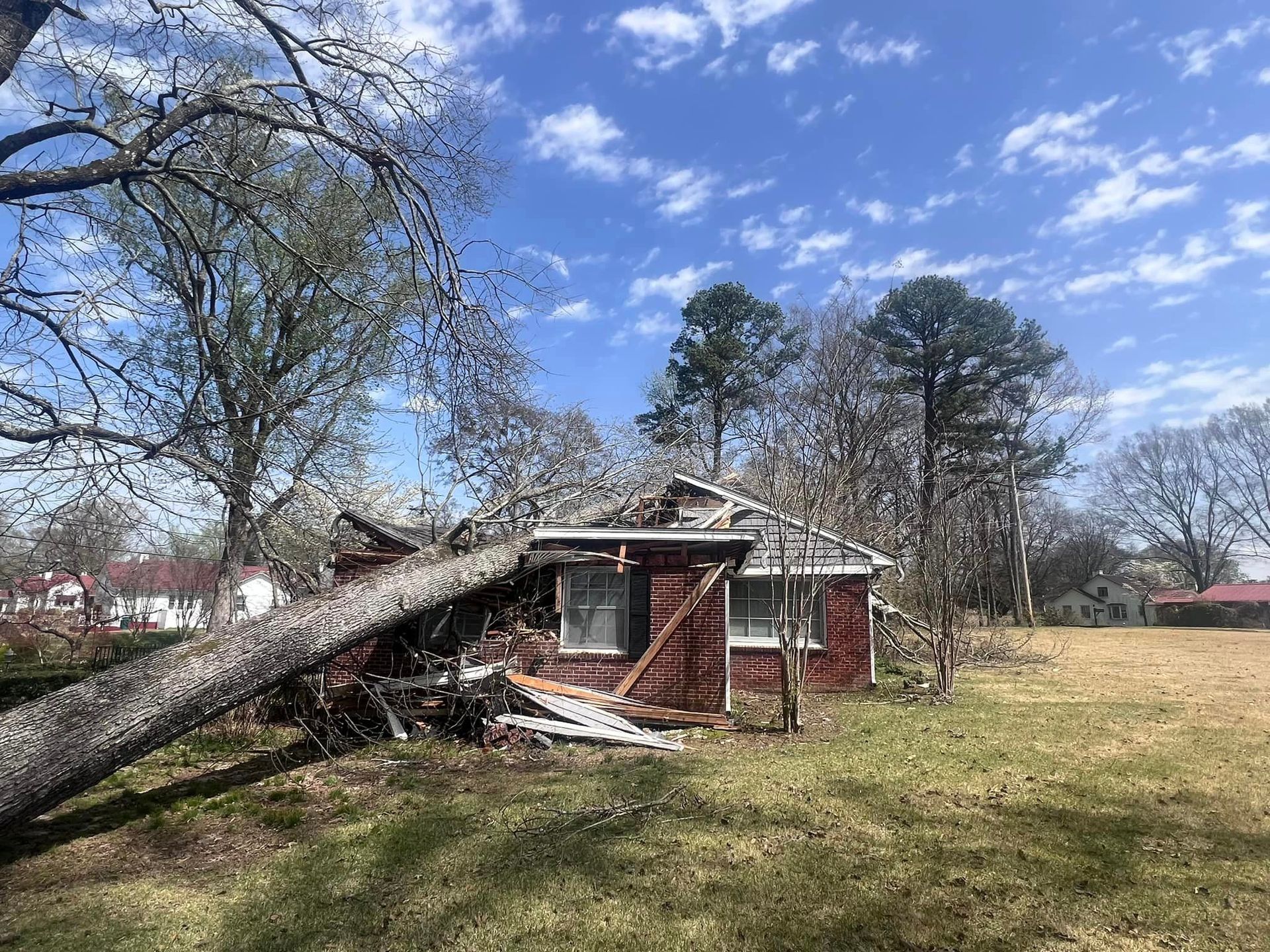 a house with a tree fallen on it in a field