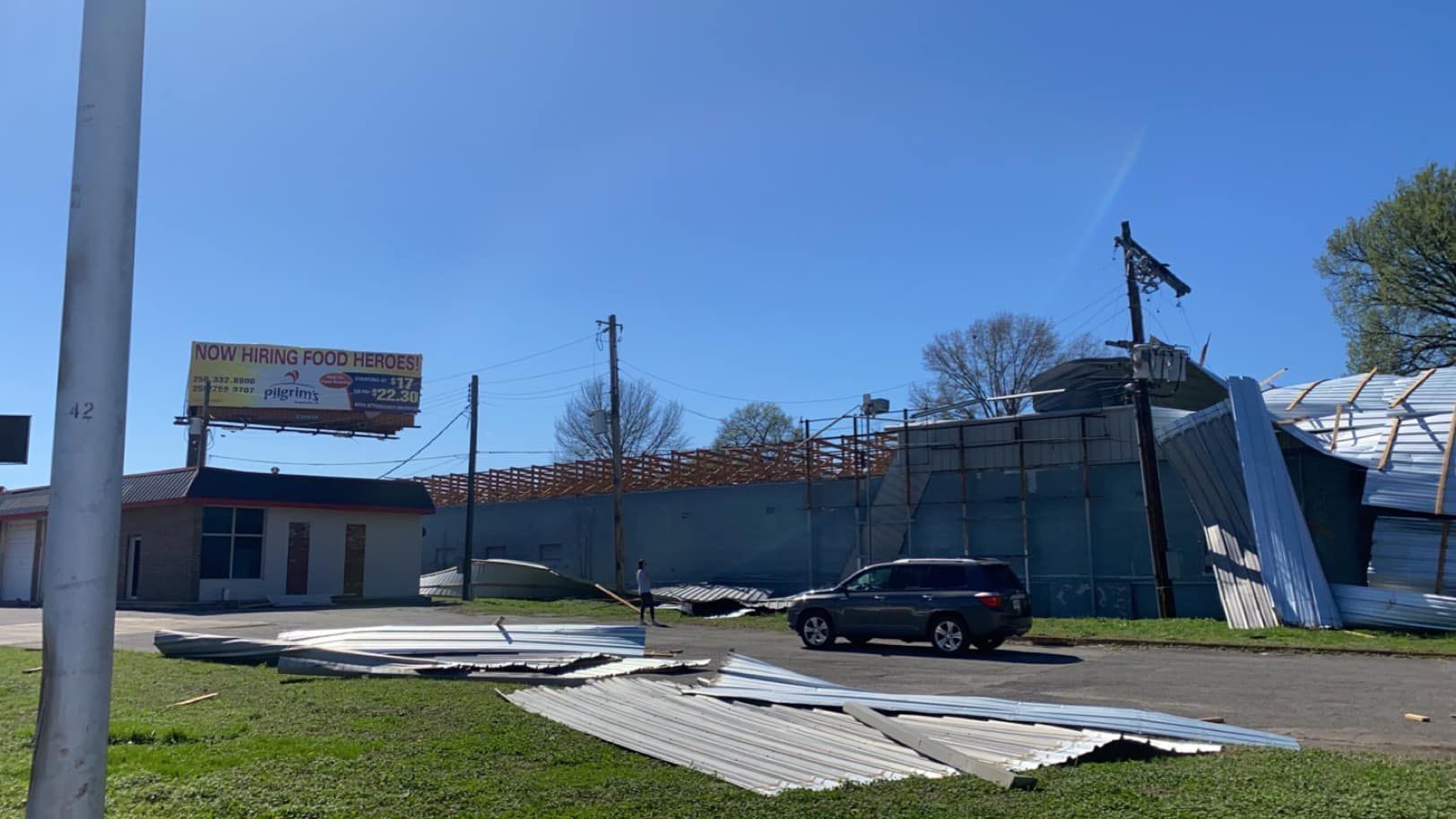 a car is parked in front of a building that has been damaged by a tornado .