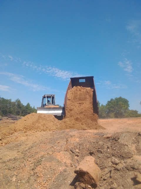 a bulldozer is loading dirt into a dump truck .