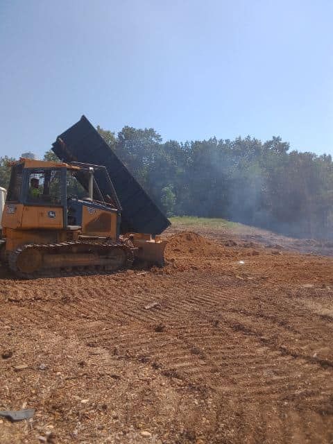 a bulldozer is loading dirt into a dump truck in a dirt field