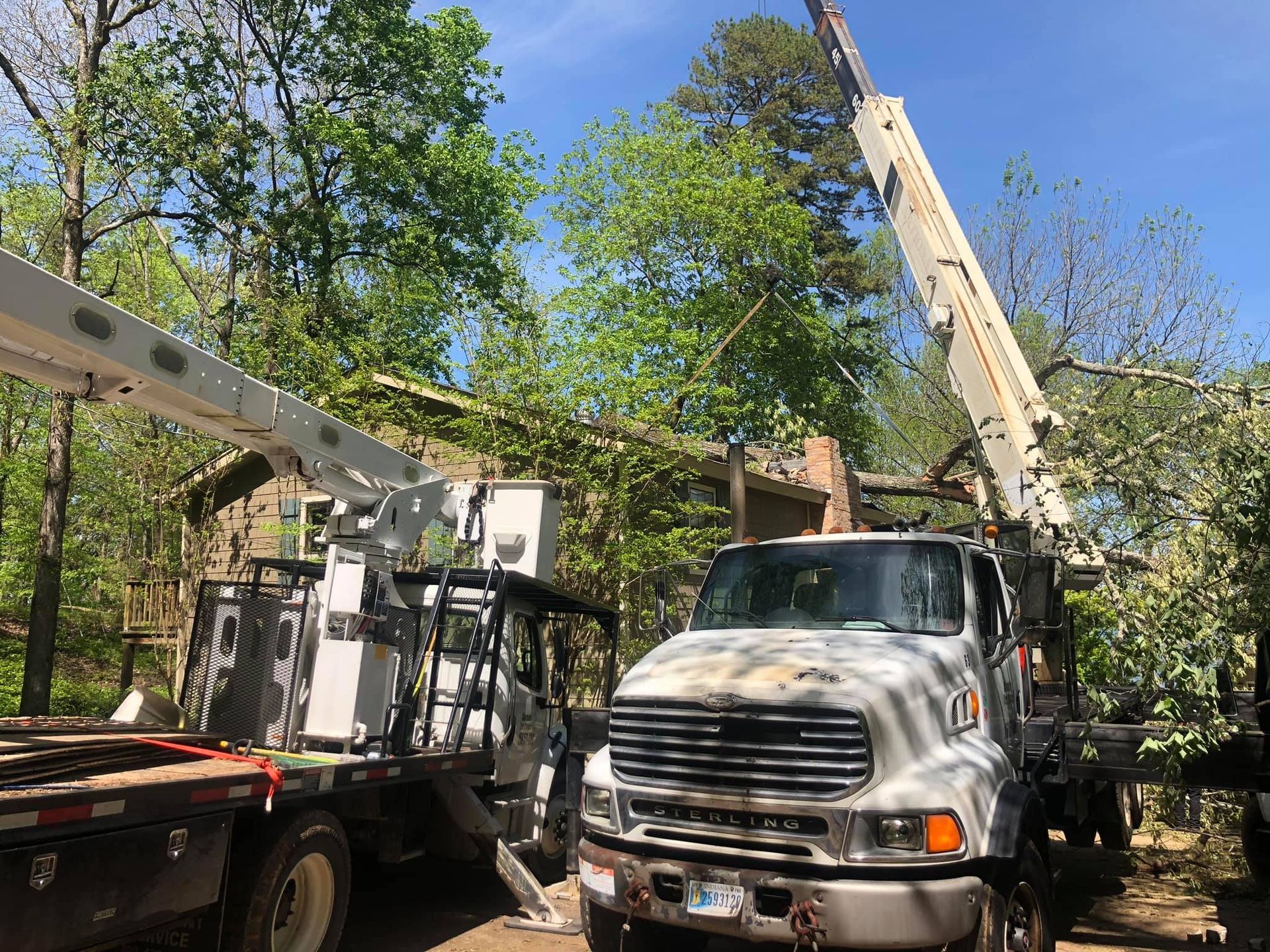 a white truck with a crane on top of it is parked in front of a house