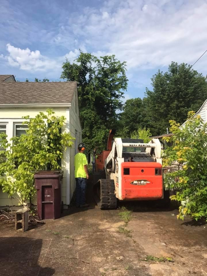 a man is standing next to a bulldozer in front of a house