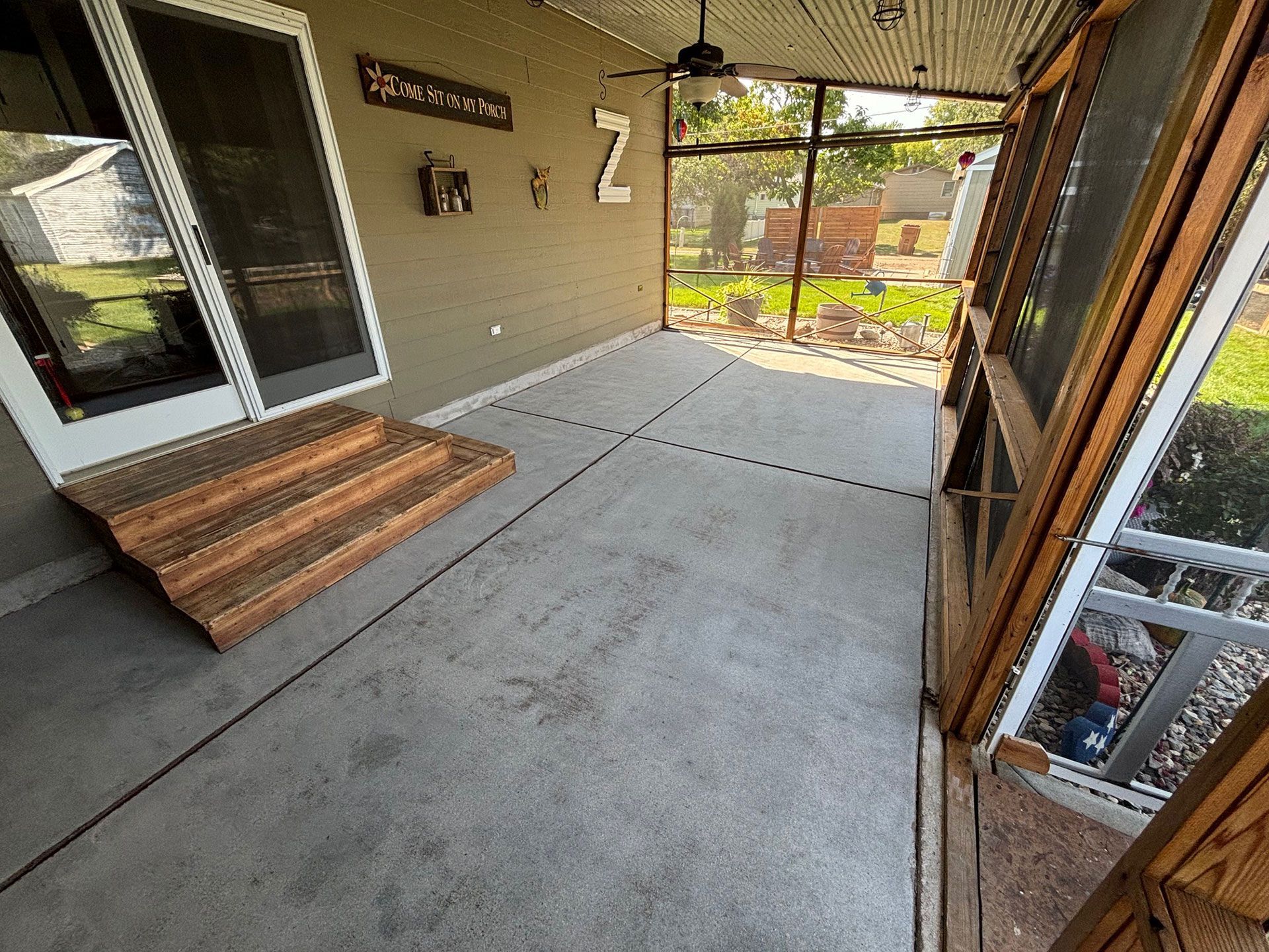 Before: A screened-in porch with stairs, a glass door, and a ceiling fan.