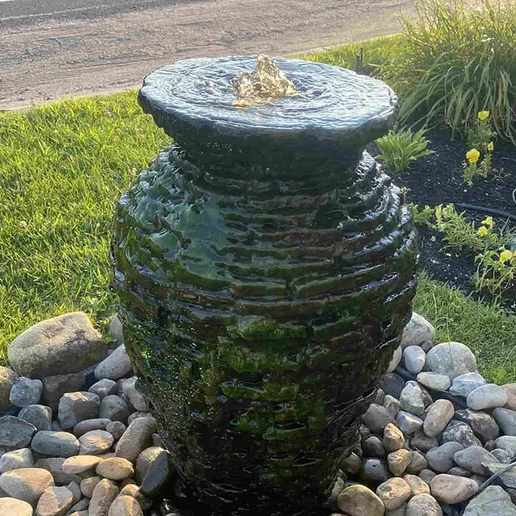 Stone water fountain in a garden, water flowing from the top.