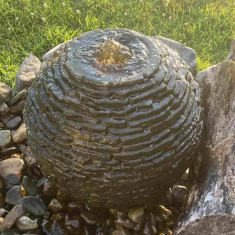 A spherical water fountain made of dark stone with water flowing from the center.