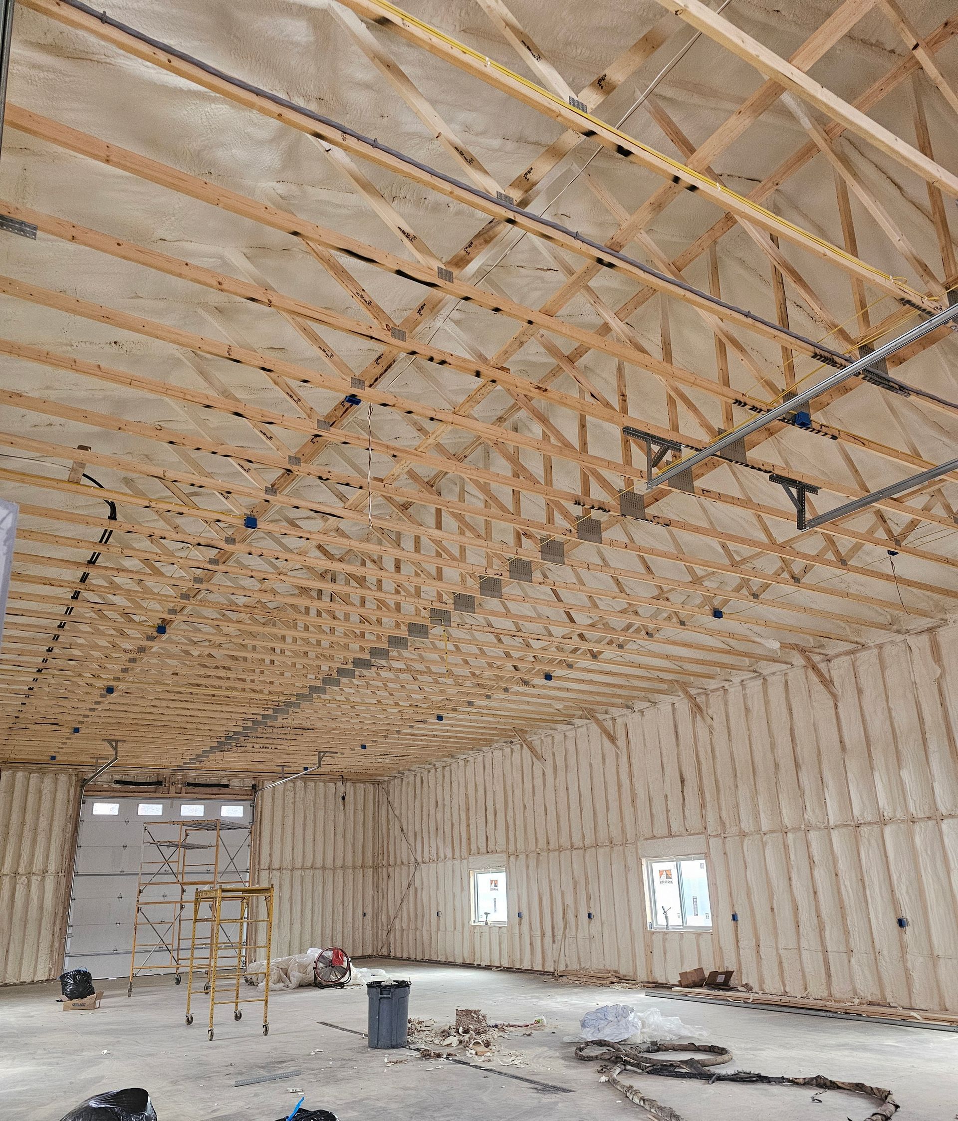 A large room with a lot of wooden beams and insulation on the ceiling.