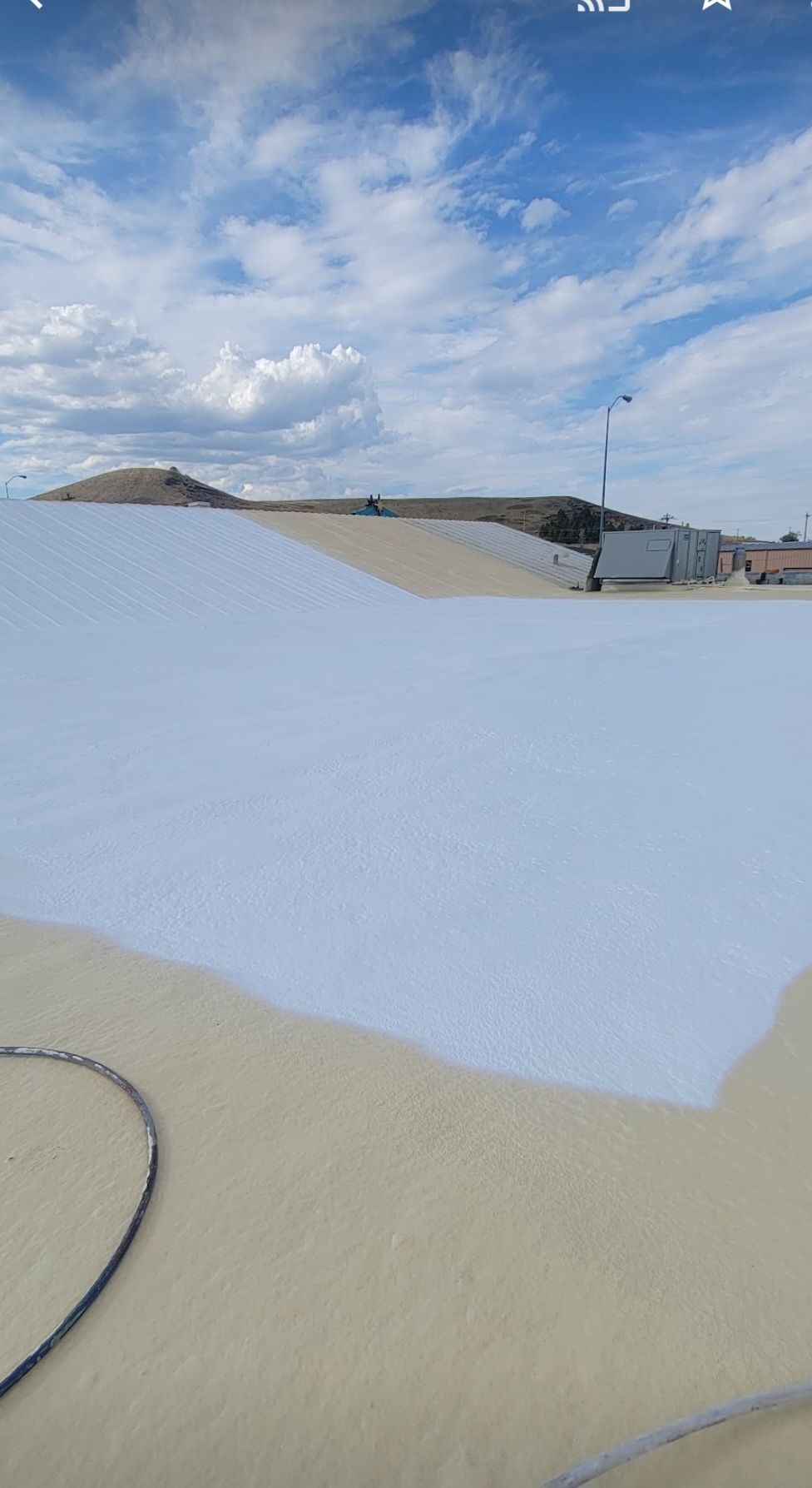 A roof is being painted white with a hose.