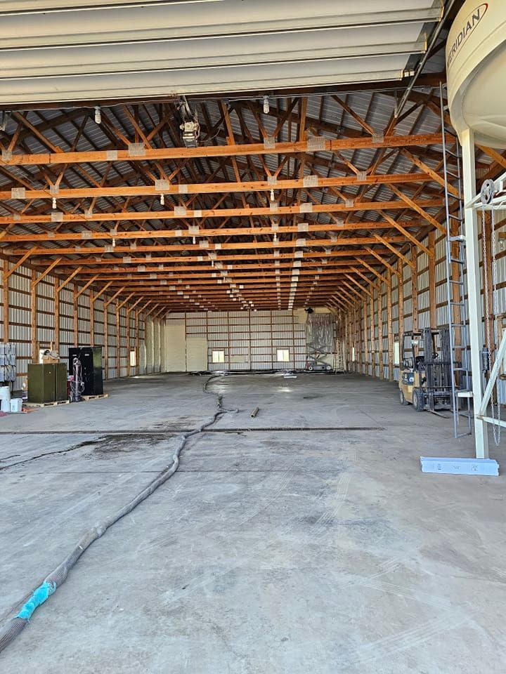 A large empty warehouse with wooden beams and a concrete floor.
