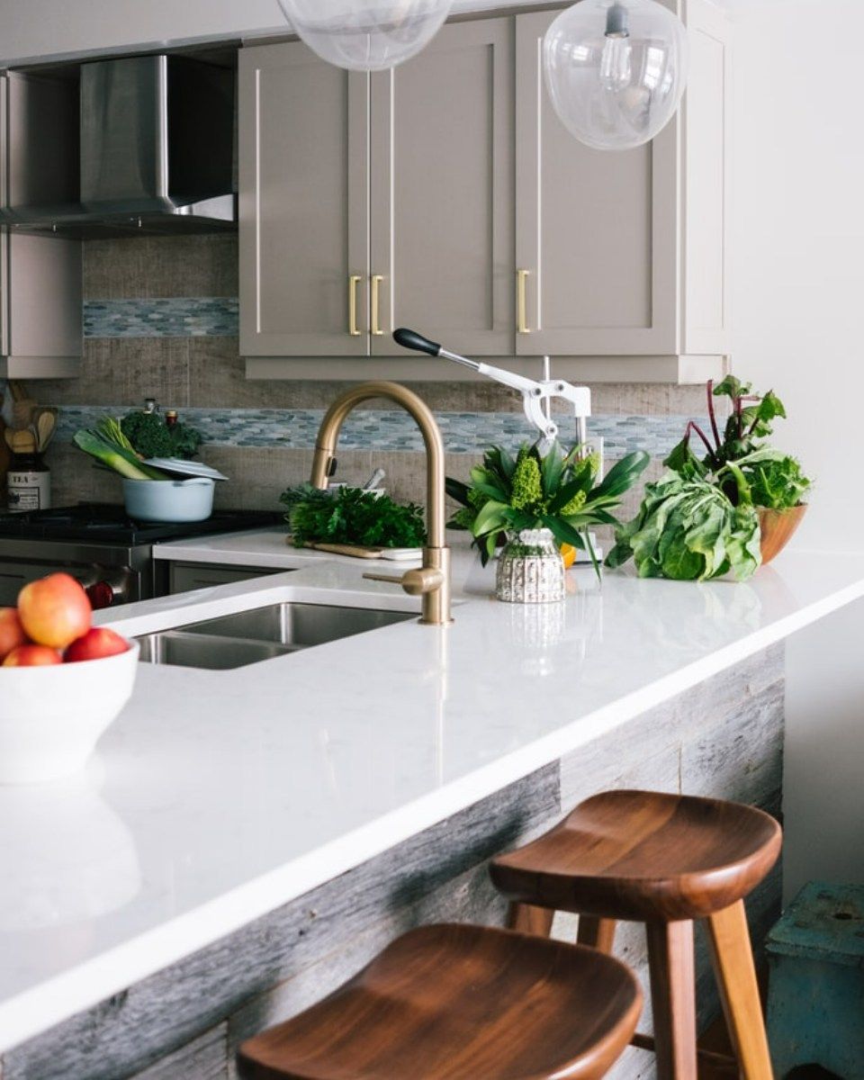 A kitchen with a sink and a bowl of fruit on the counter