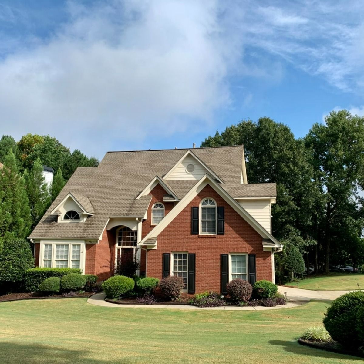 A large brick house with a large lawn in front of it
