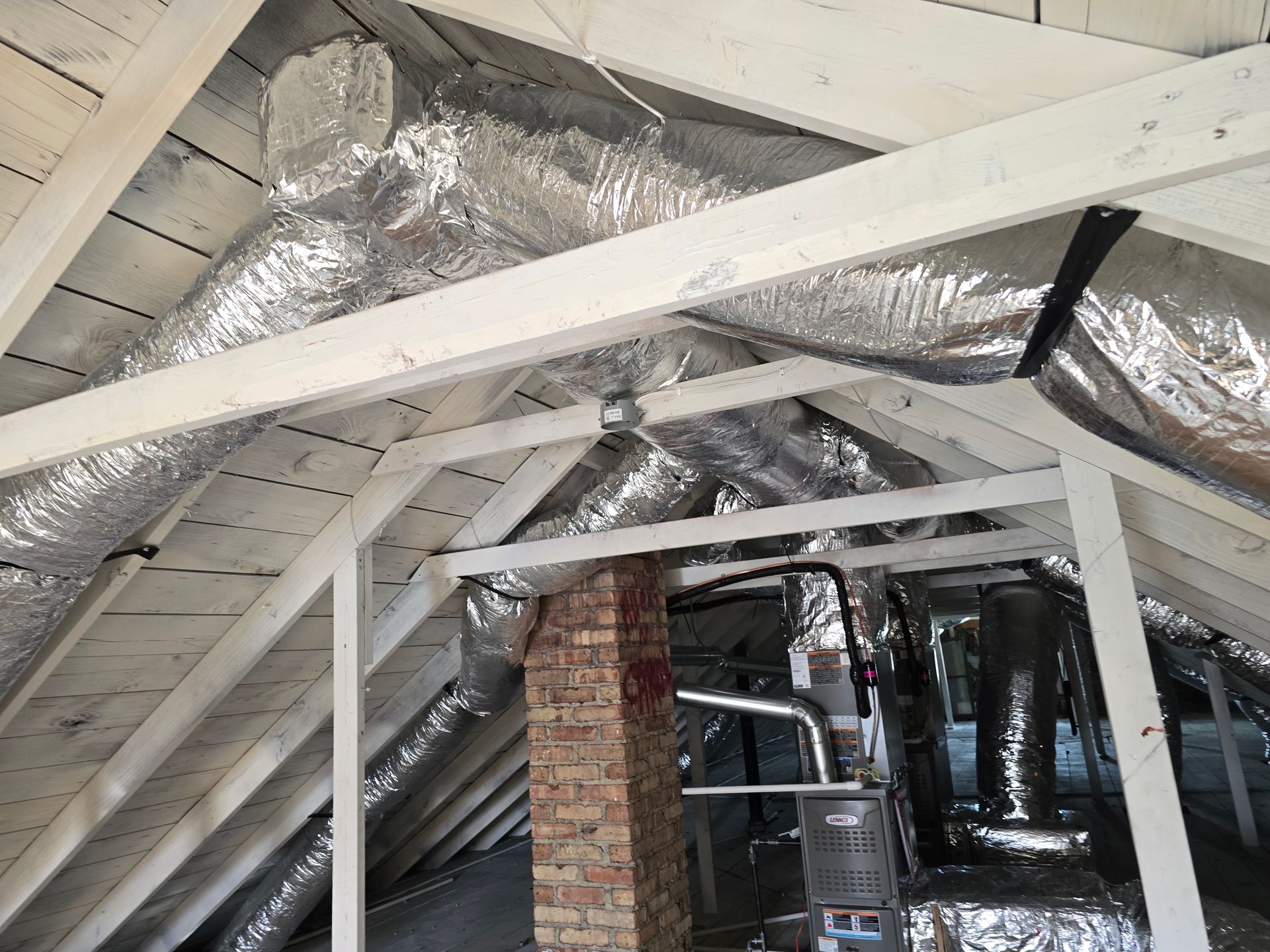 A technician in work coveralls using gloved hands to install or adjust a ceiling air vent.