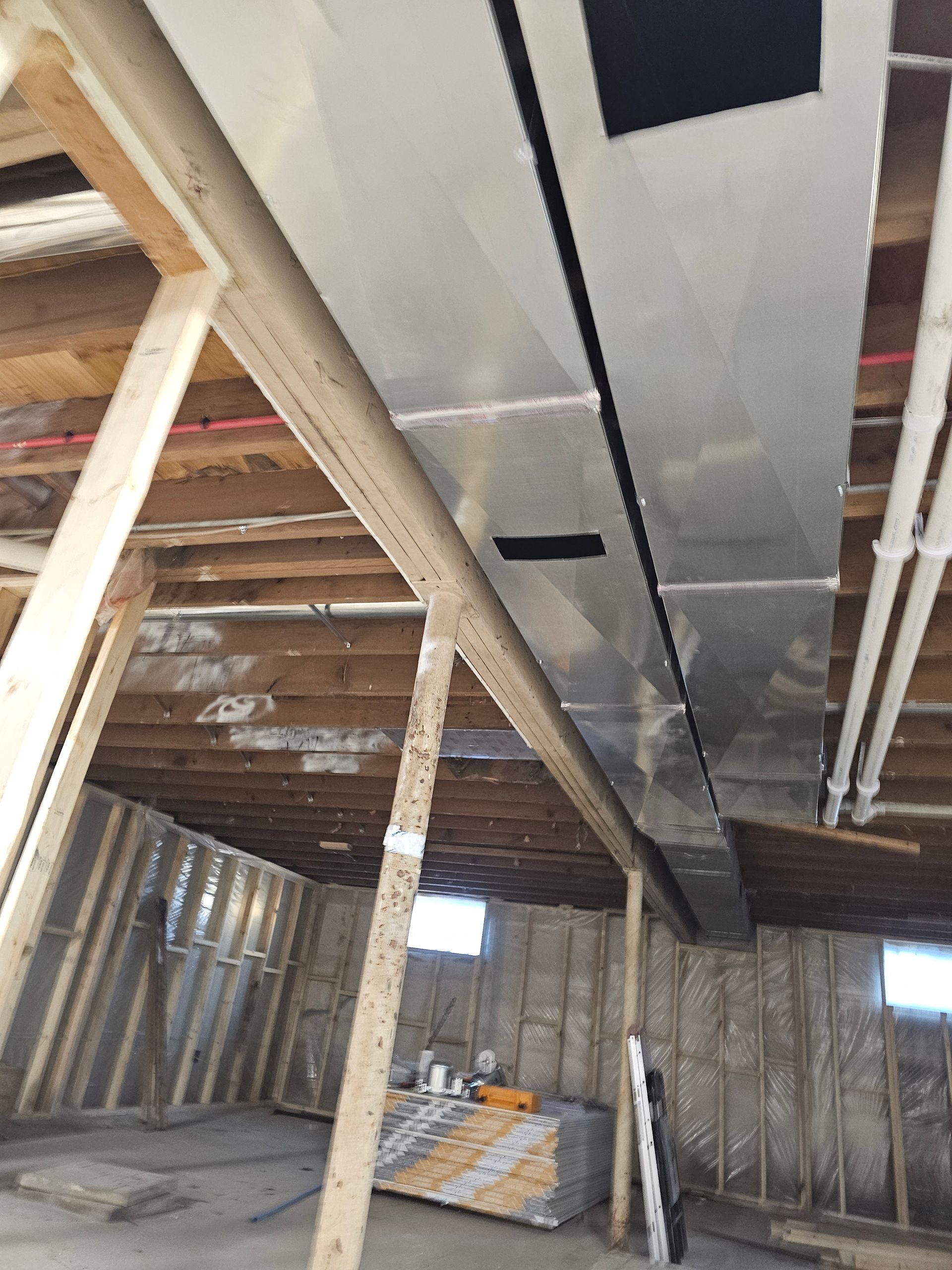 Partially built interior with exposed framing, insulation, and ducts under a wooden ceiling