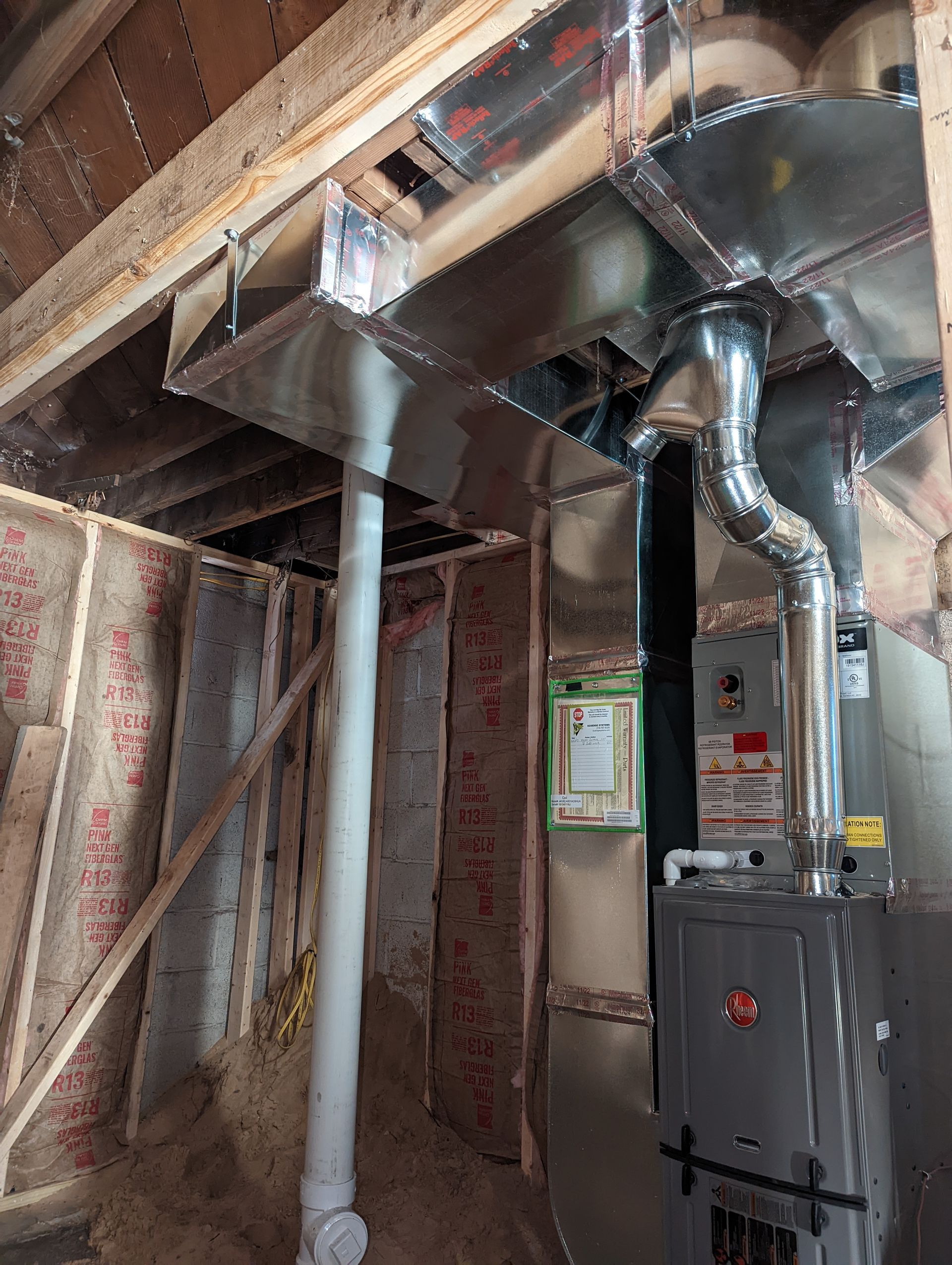 Basement utility room with exposed ductwork, furnace, and white support columns.
