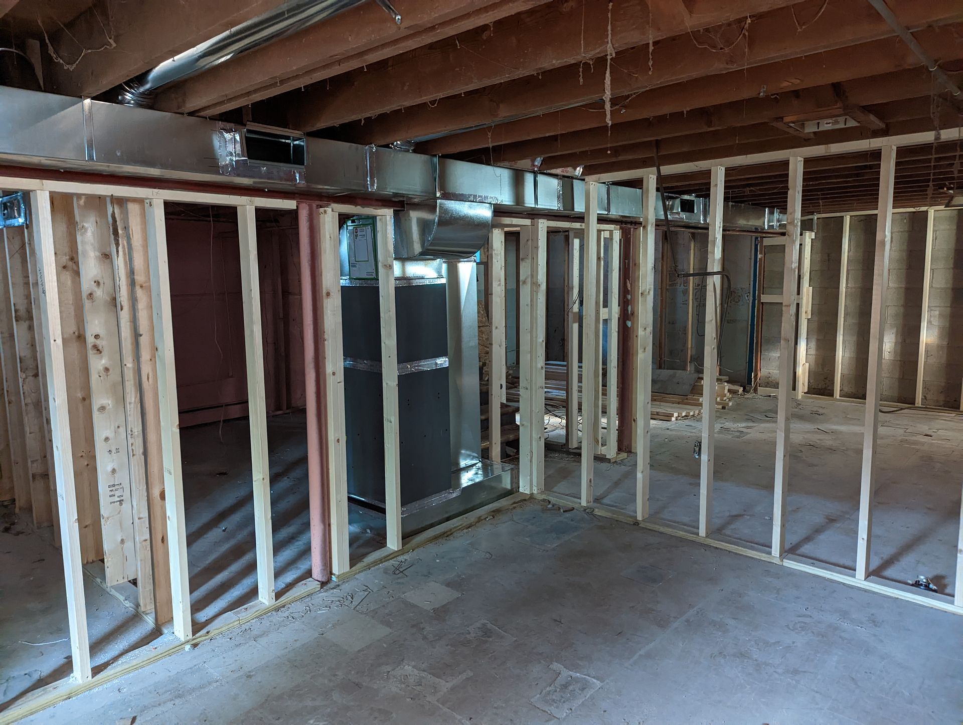 Unfinished basement framing with exposed studs, concrete floor, and ceiling joists.