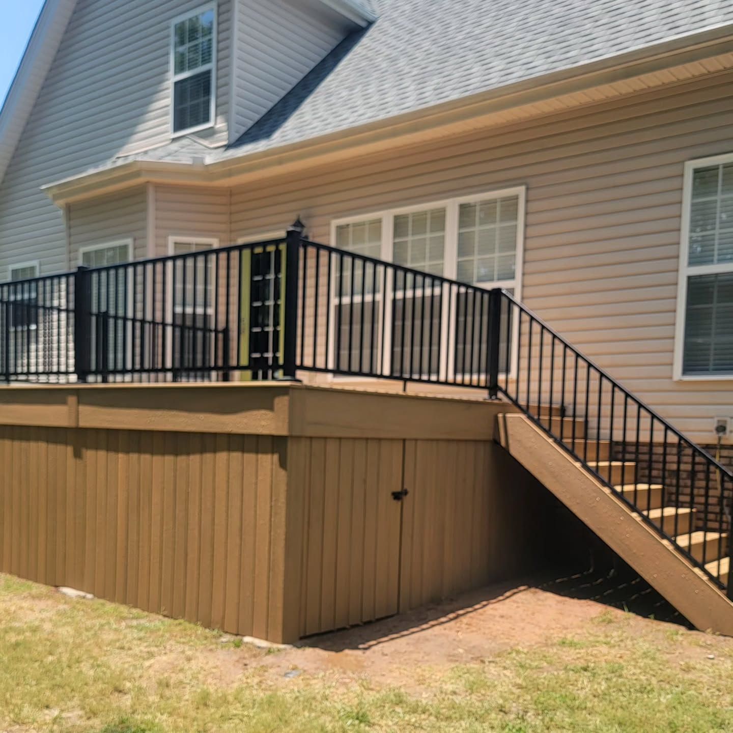 A wooden fence is sitting on top of a dirt hill next to a house.