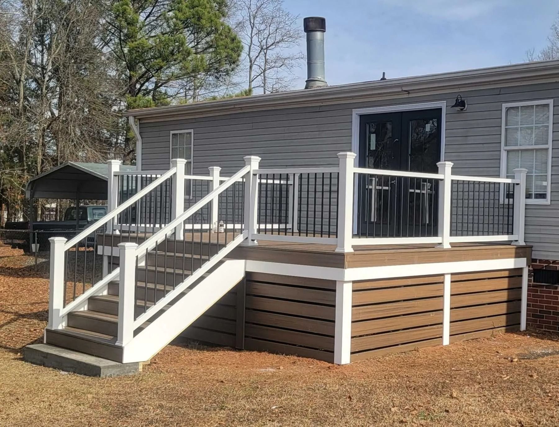 A mobile home with a deck and stairs in front of it