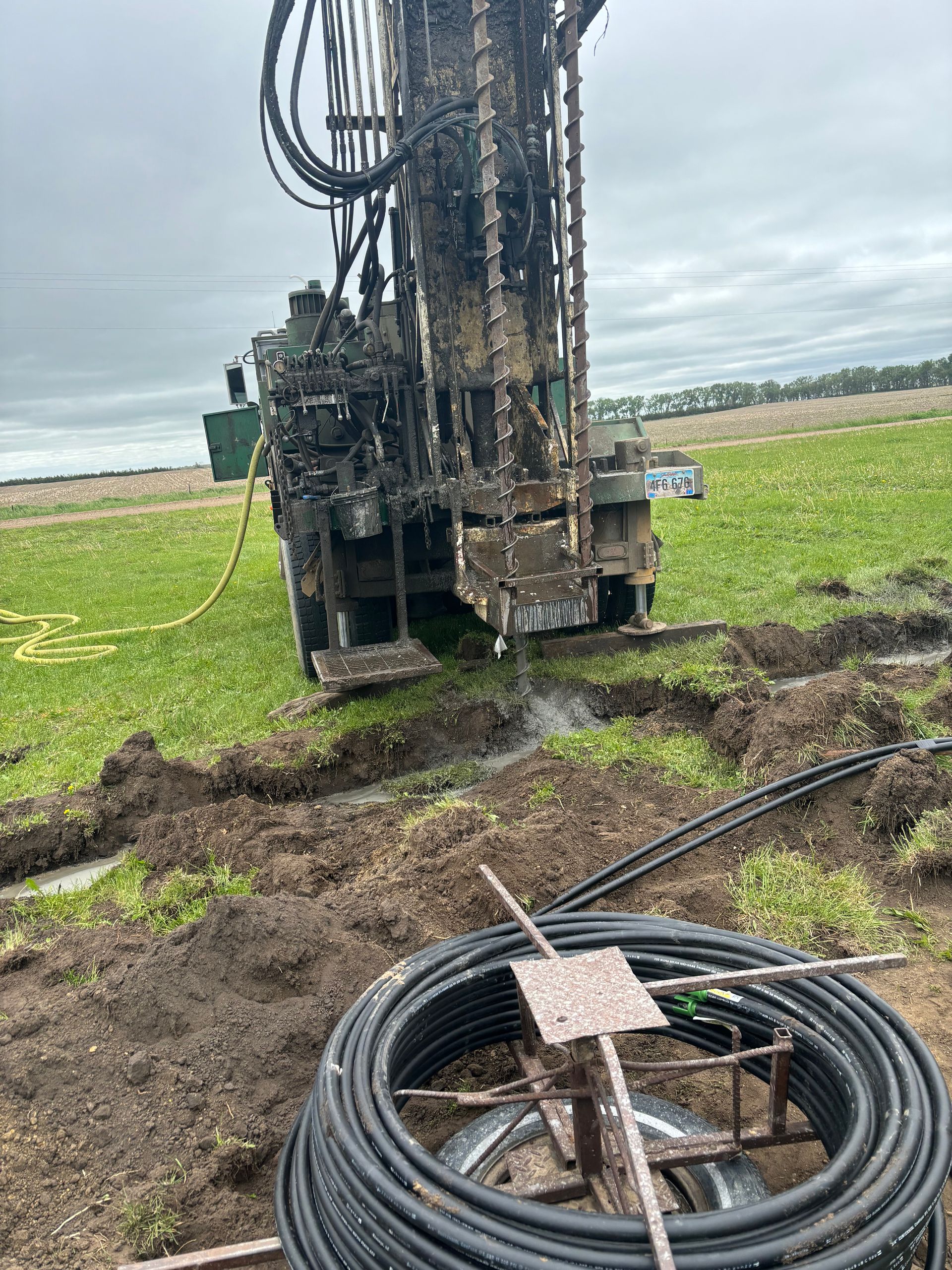A large machine is drilling a hole in the ground in a field.