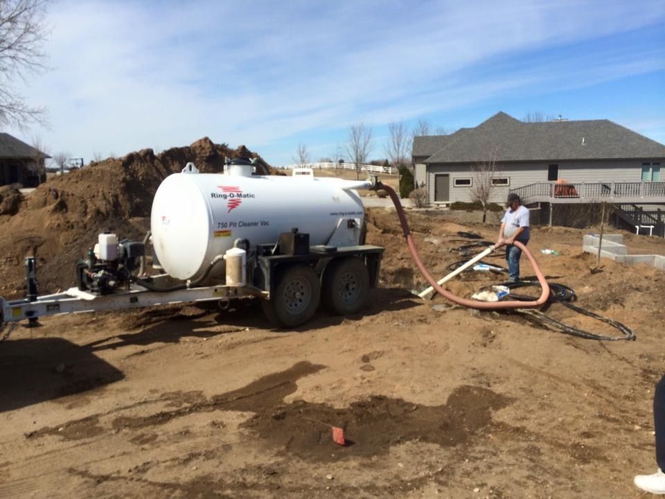 A man is standing next to a large white tank on a trailer.