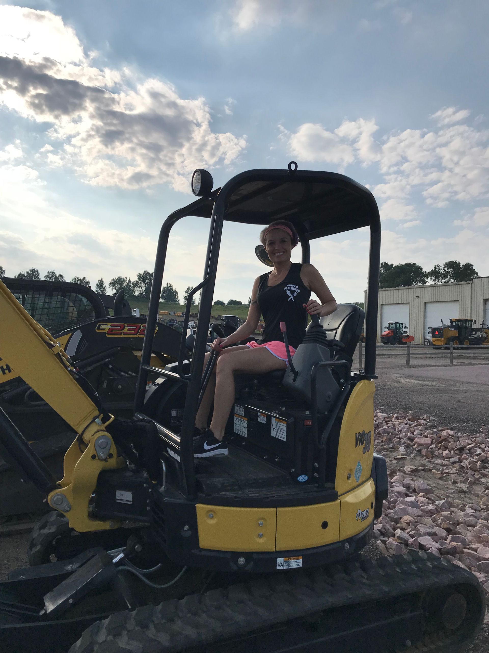 A woman is sitting in the driver 's seat of a yellow excavator.