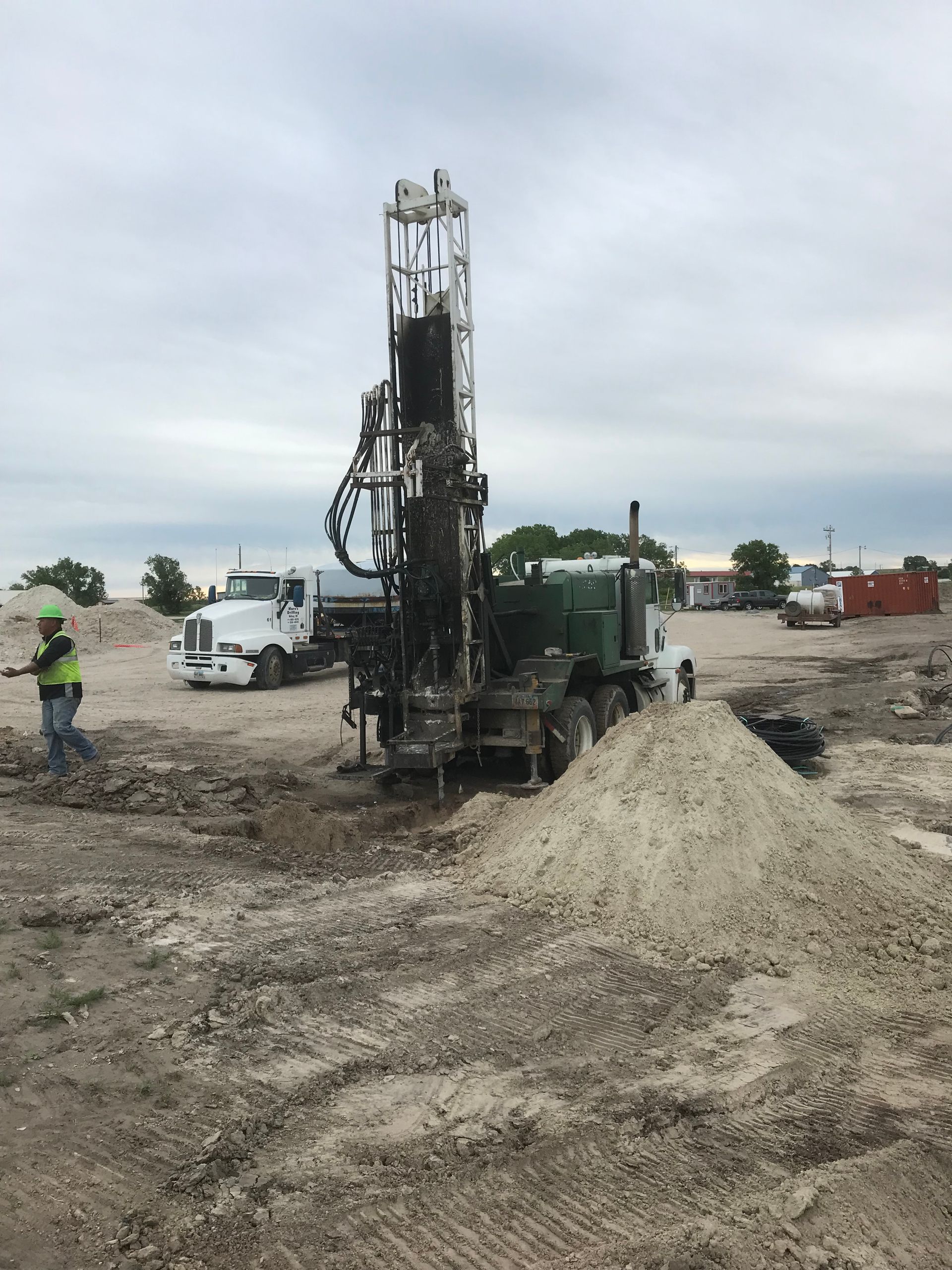 A man is standing next to a large machine in a dirt field.