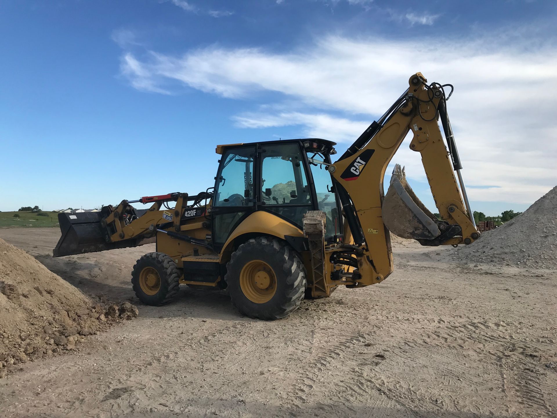 A yellow and black backhoe is sitting in a dirt field.
