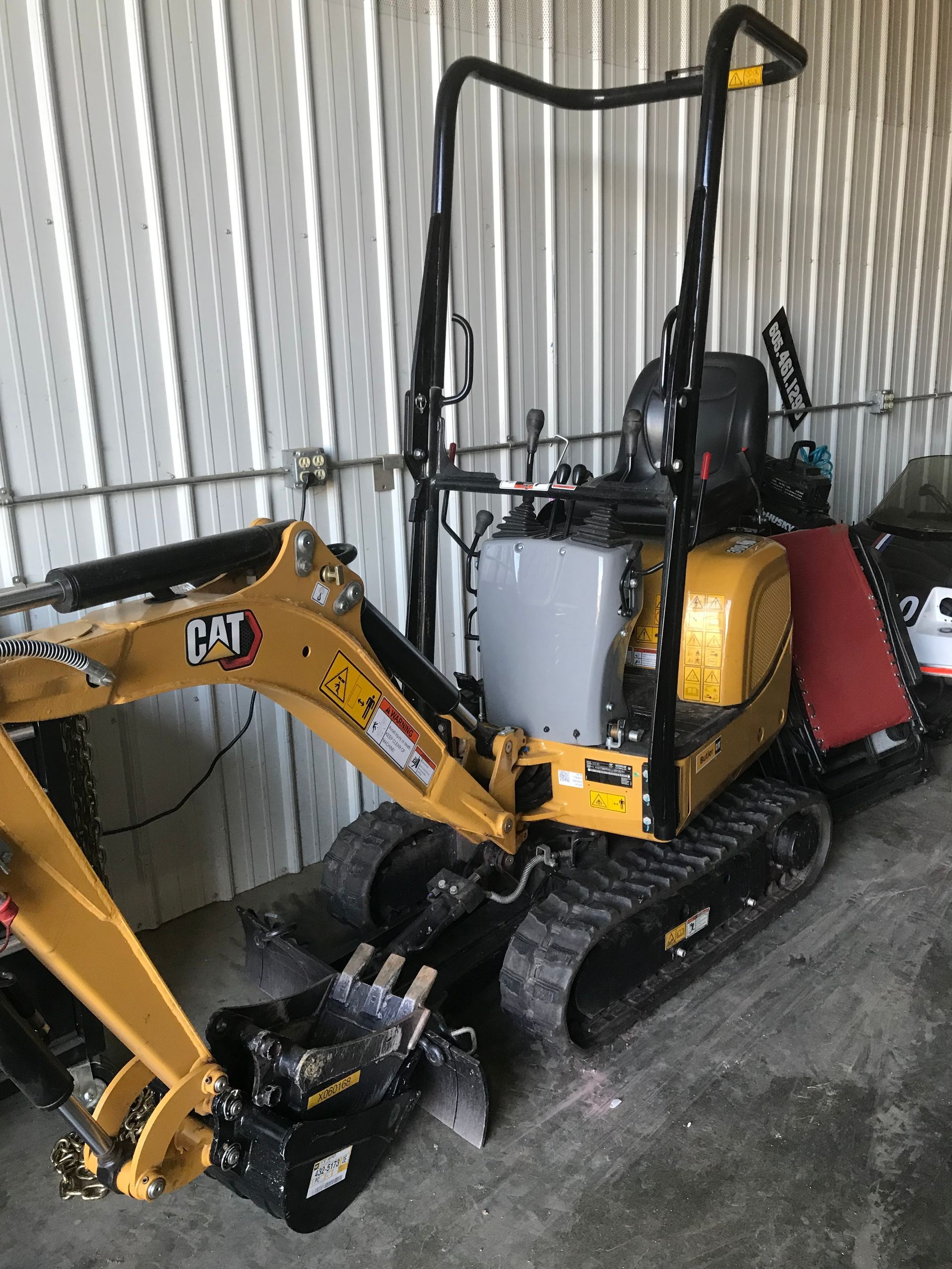 A small yellow cat excavator is parked in a garage.