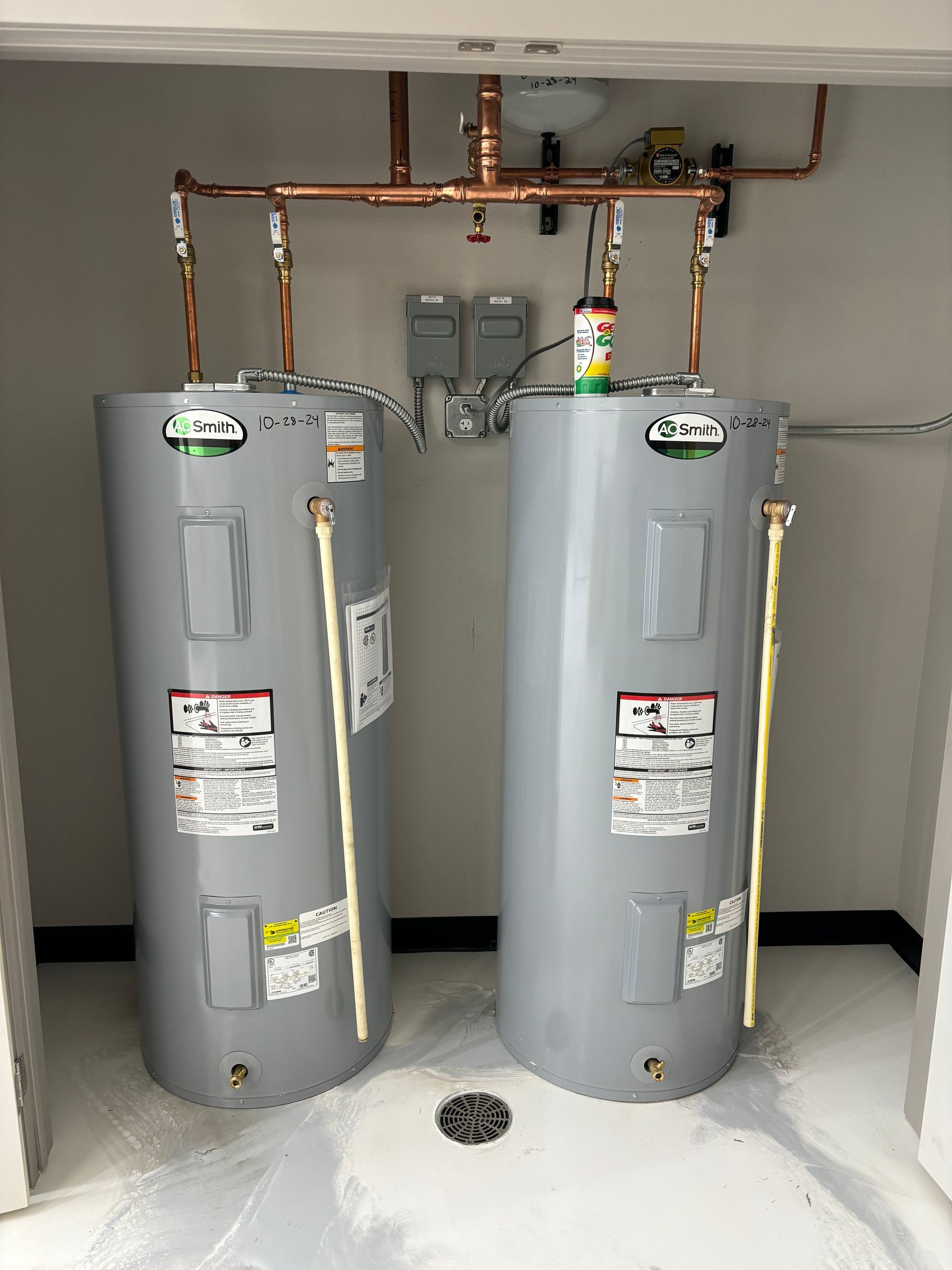 Two water heaters are sitting next to each other in a room.