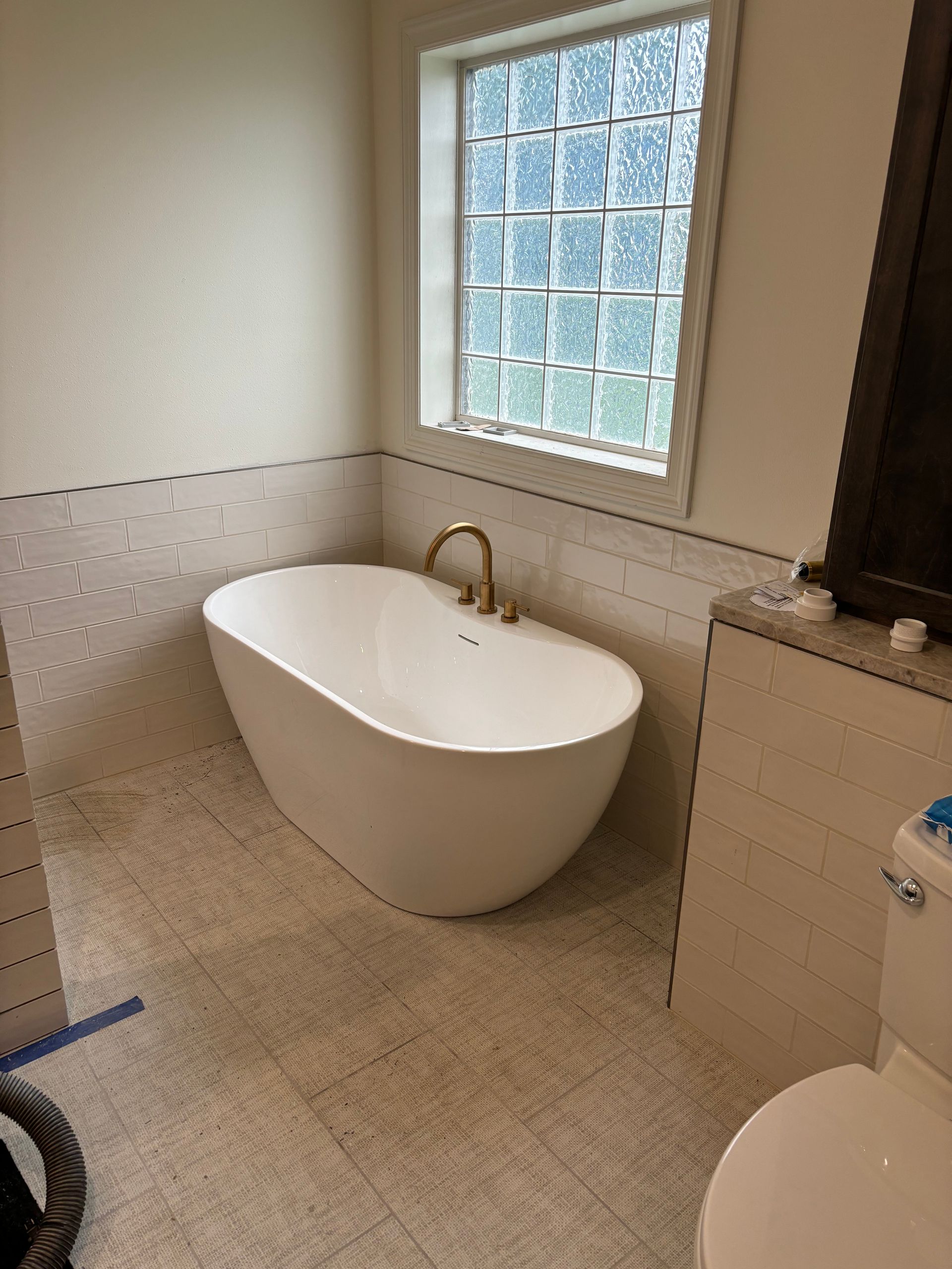 A bathroom with a bathtub, toilet, and window.