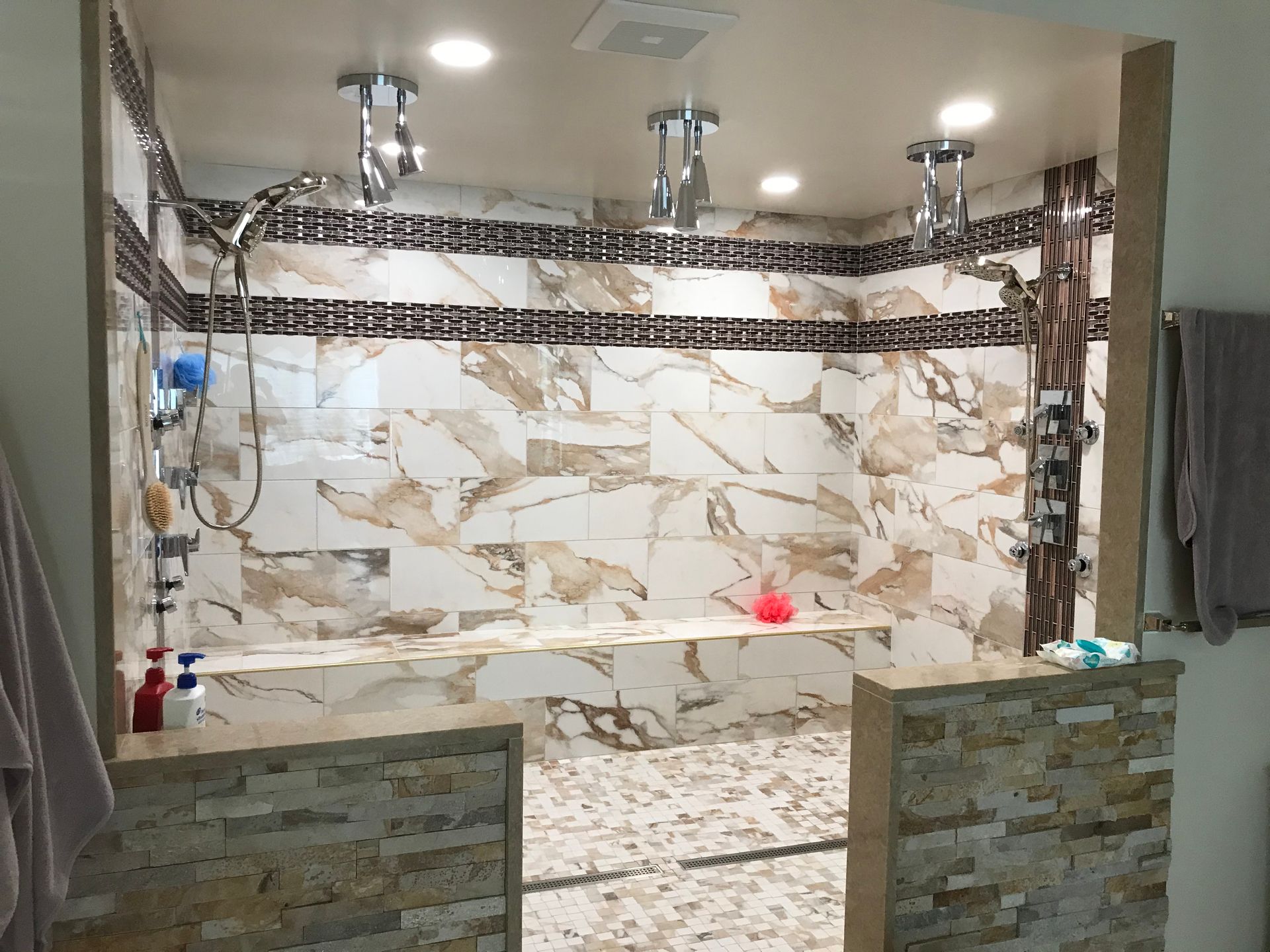 A bathroom with marble tiles and a walk in shower.