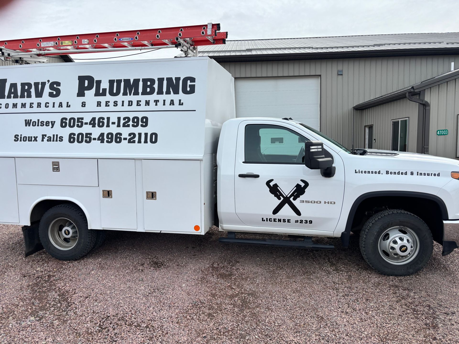 A white truck for harv's plumbing is parked in front of a building