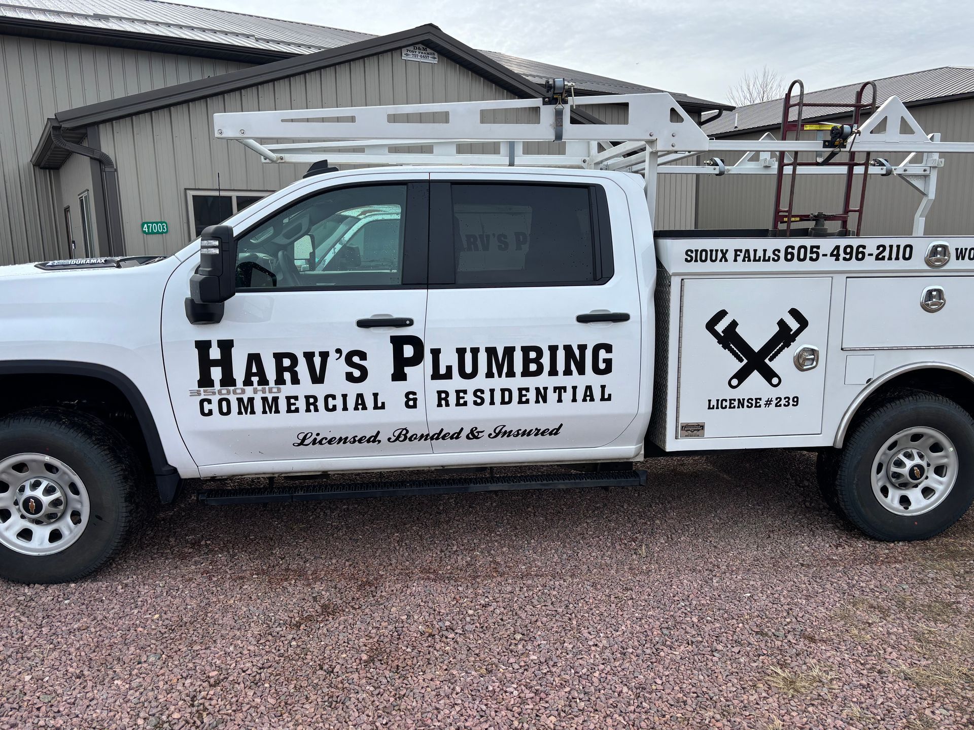 A white truck for harv's plumbing is parked in front of a building
