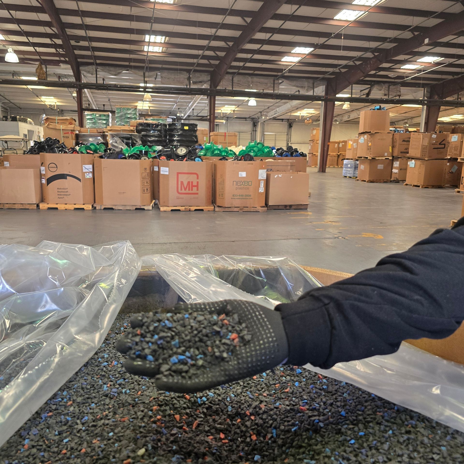 A person wearing a glove is holding a pile of recycled materials