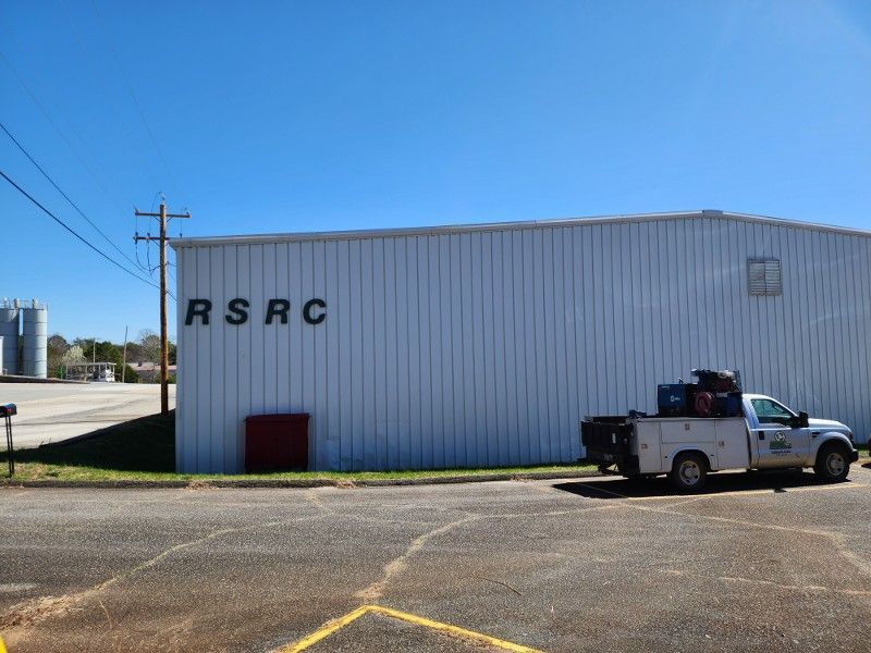 A white truck is parked in front of a building that says RSRC