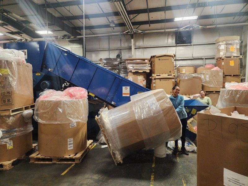 A warehouse filled with lots of cardboard boxes and a blue conveyor belt