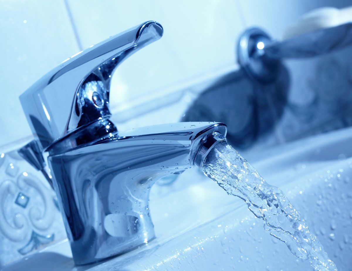 Chrome faucet with water pouring into a white sink, blue tones.