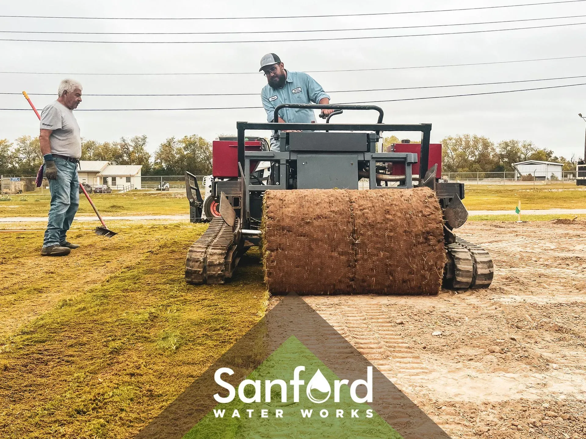 Two men rolling out sod with a tracked machine for Sanford Water Works. Cloudy day.
