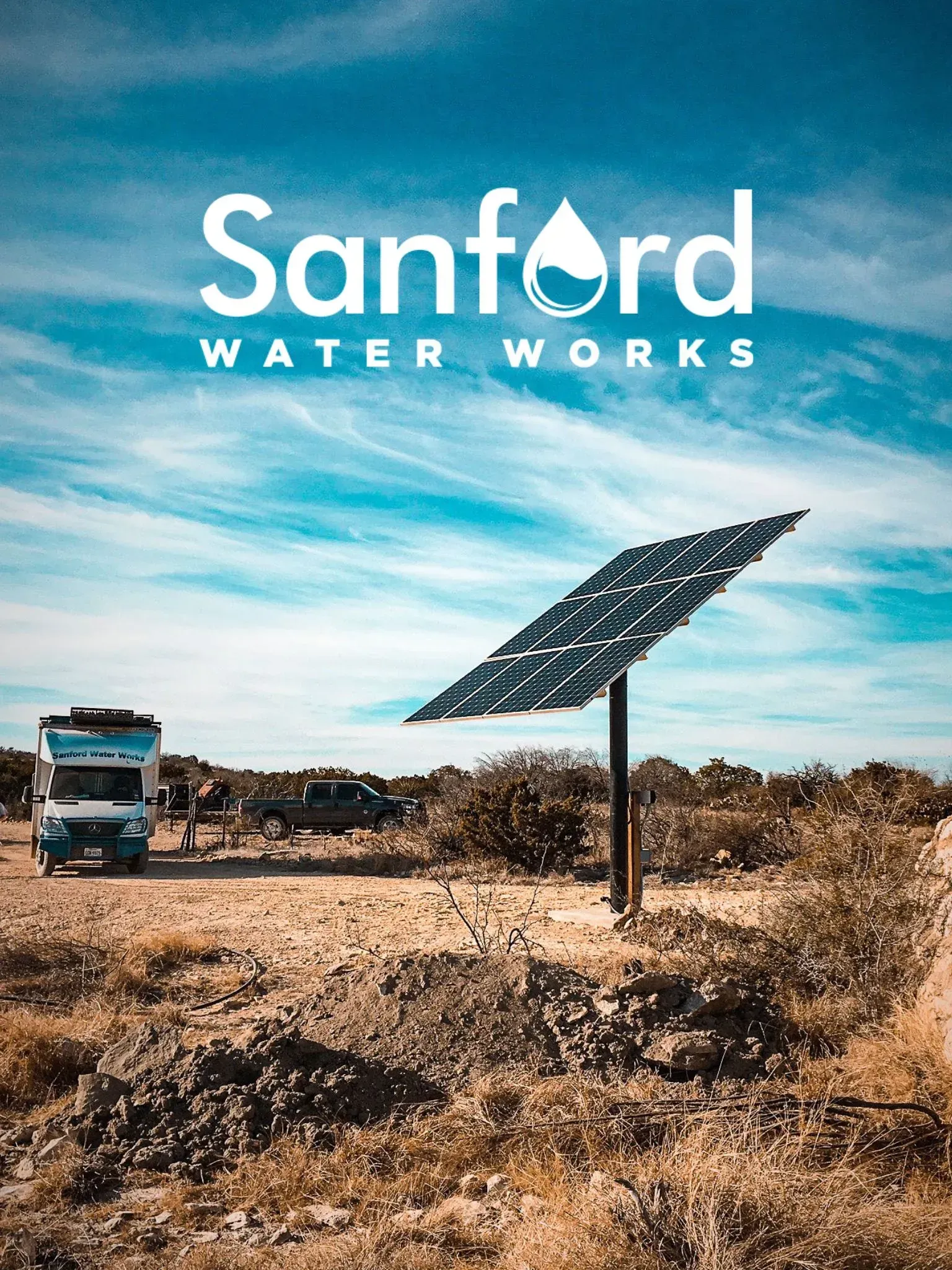 Solar panel at Sanford Water Works with RV and vehicles in a desert landscape under a blue sky.