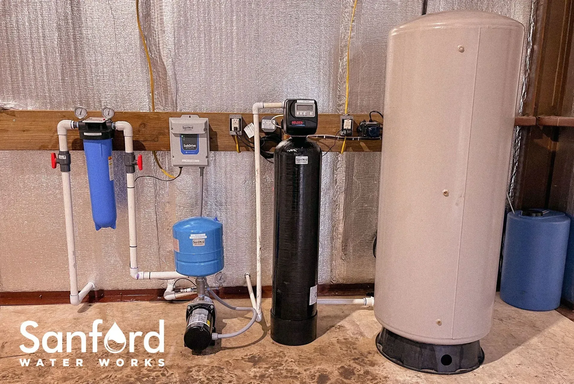 Water filtration system with tanks and plumbing in a utility room.