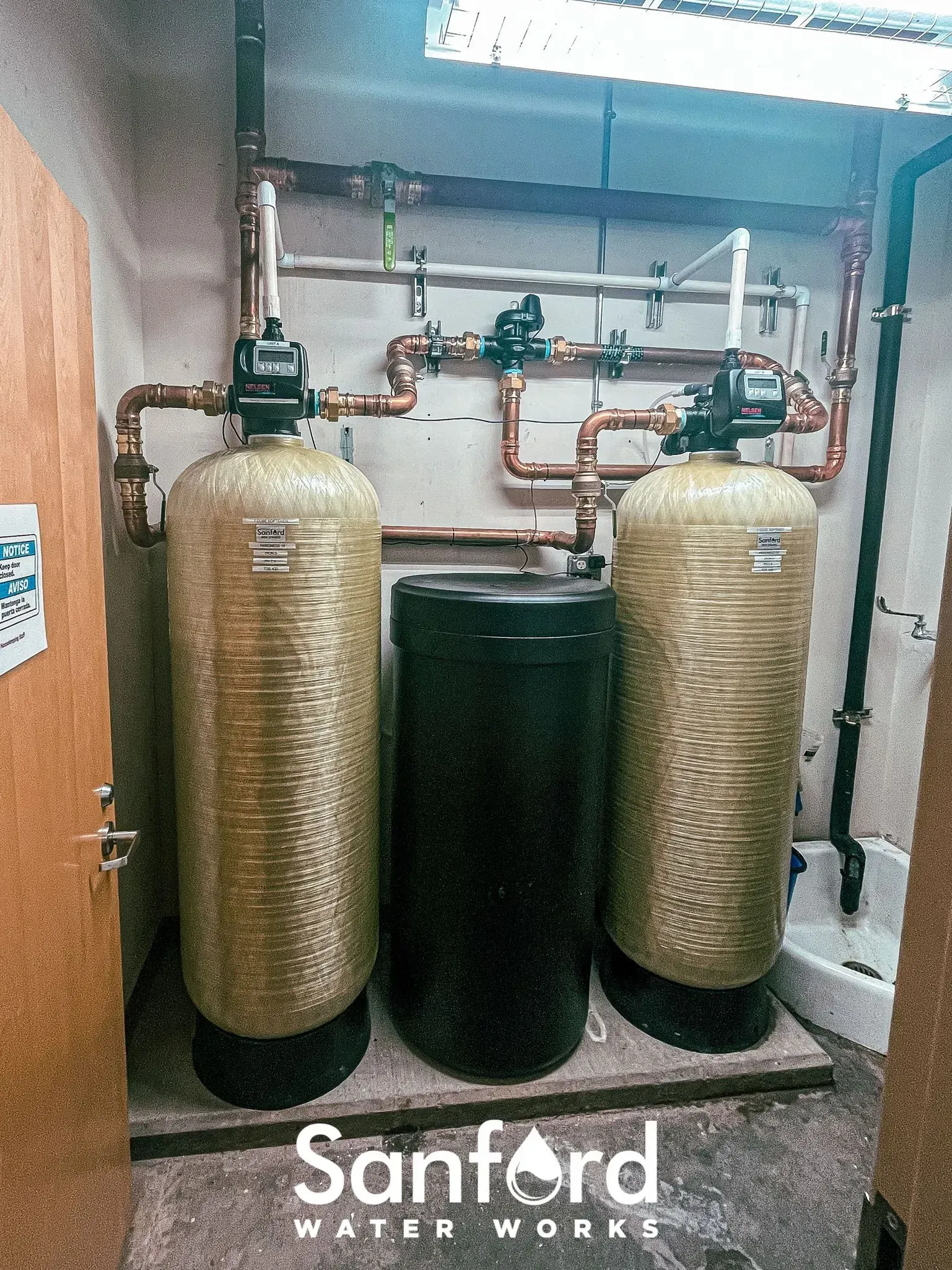 Water filtration system with two gold tanks, a black tank, and copper piping.