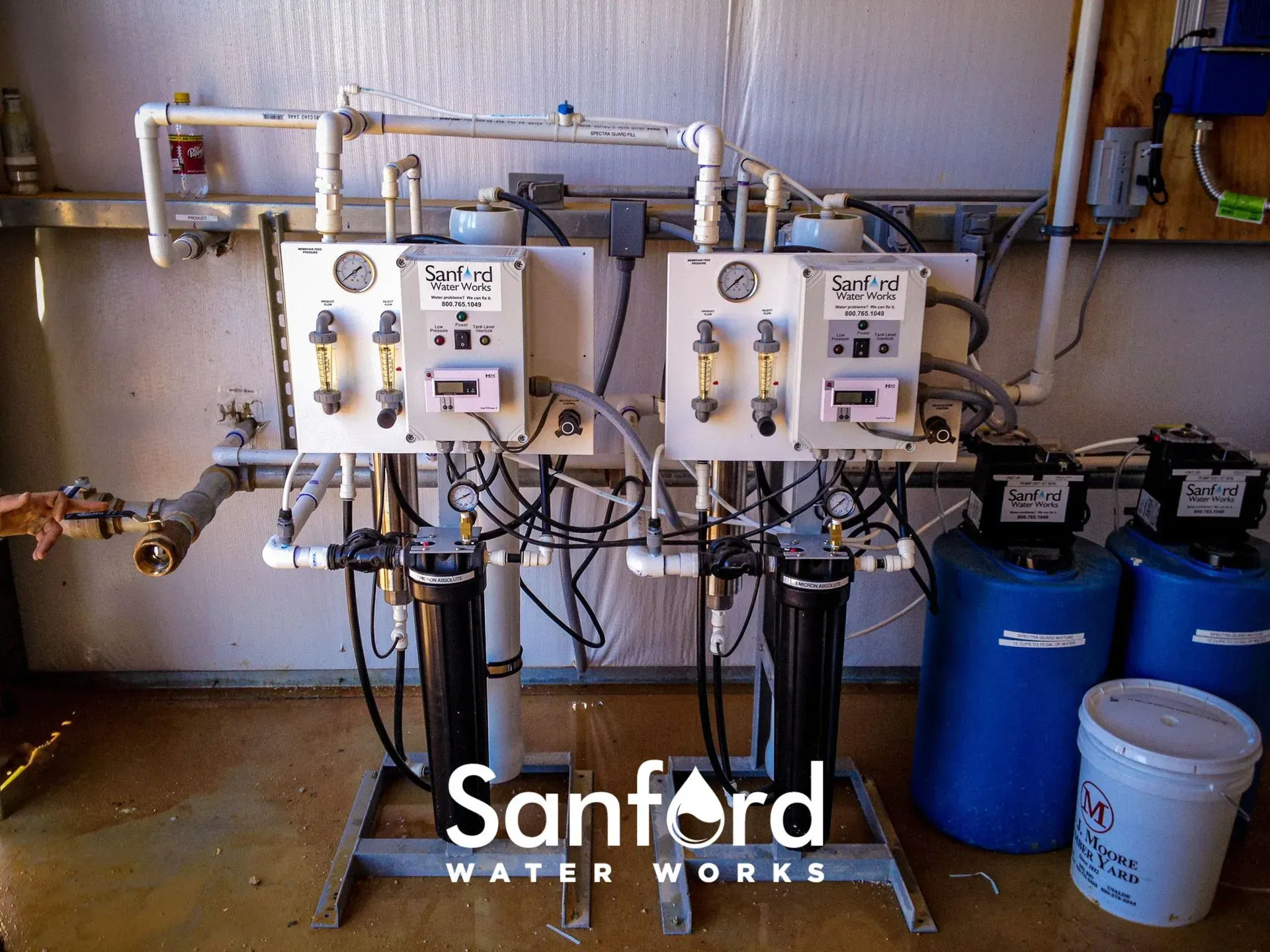 Water filtration system with white control panels, gauges, and black filters. Sanford Water Works logo visible.