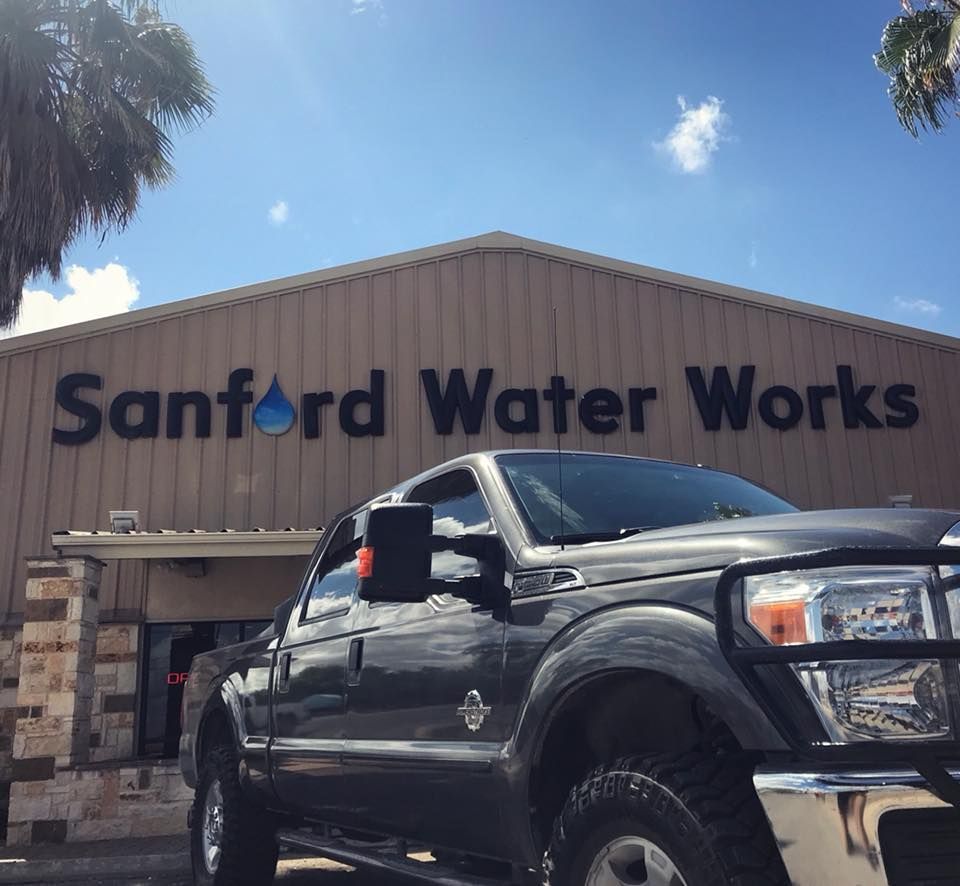 Black pickup truck parked in front of Sanford Water Works building under a blue sky