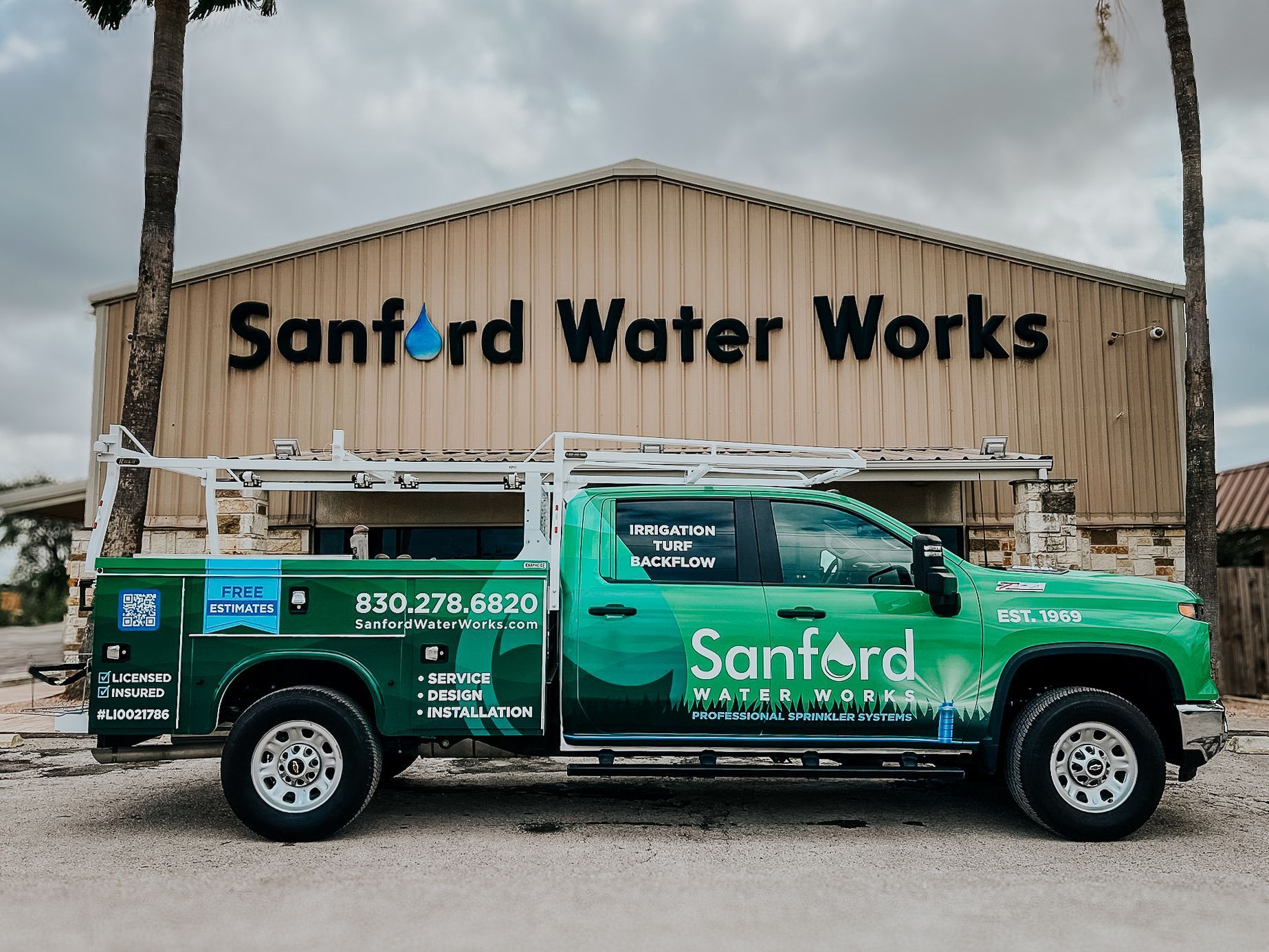 Green Sanford Water Works truck parked in front of a building with the company name on it.